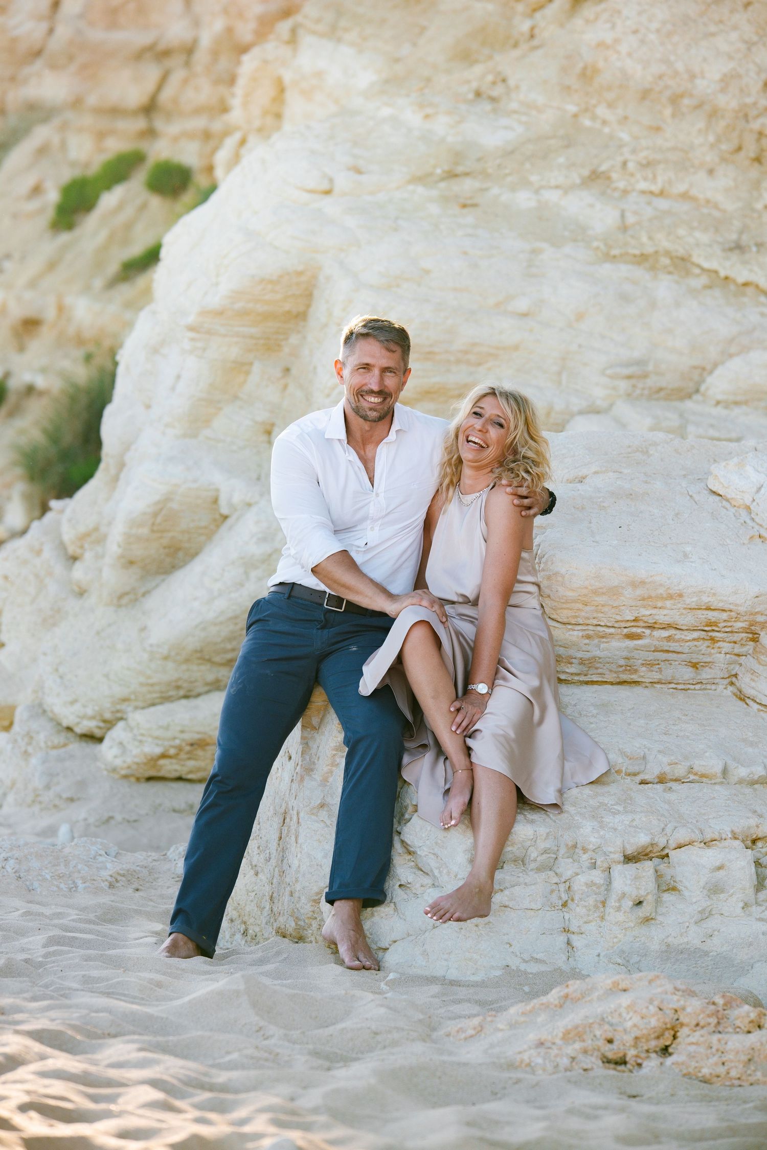 Couple sitting together on the rocks facing the ocean