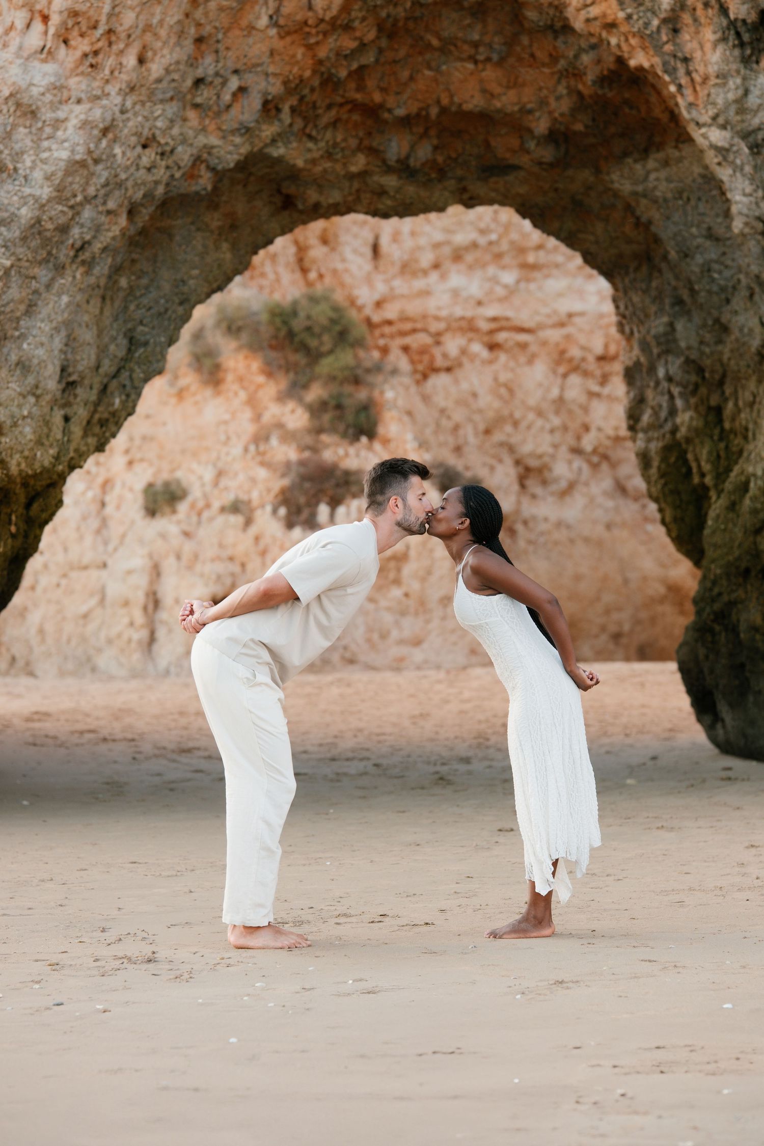 couple kissing in a funny way under the rocky arch