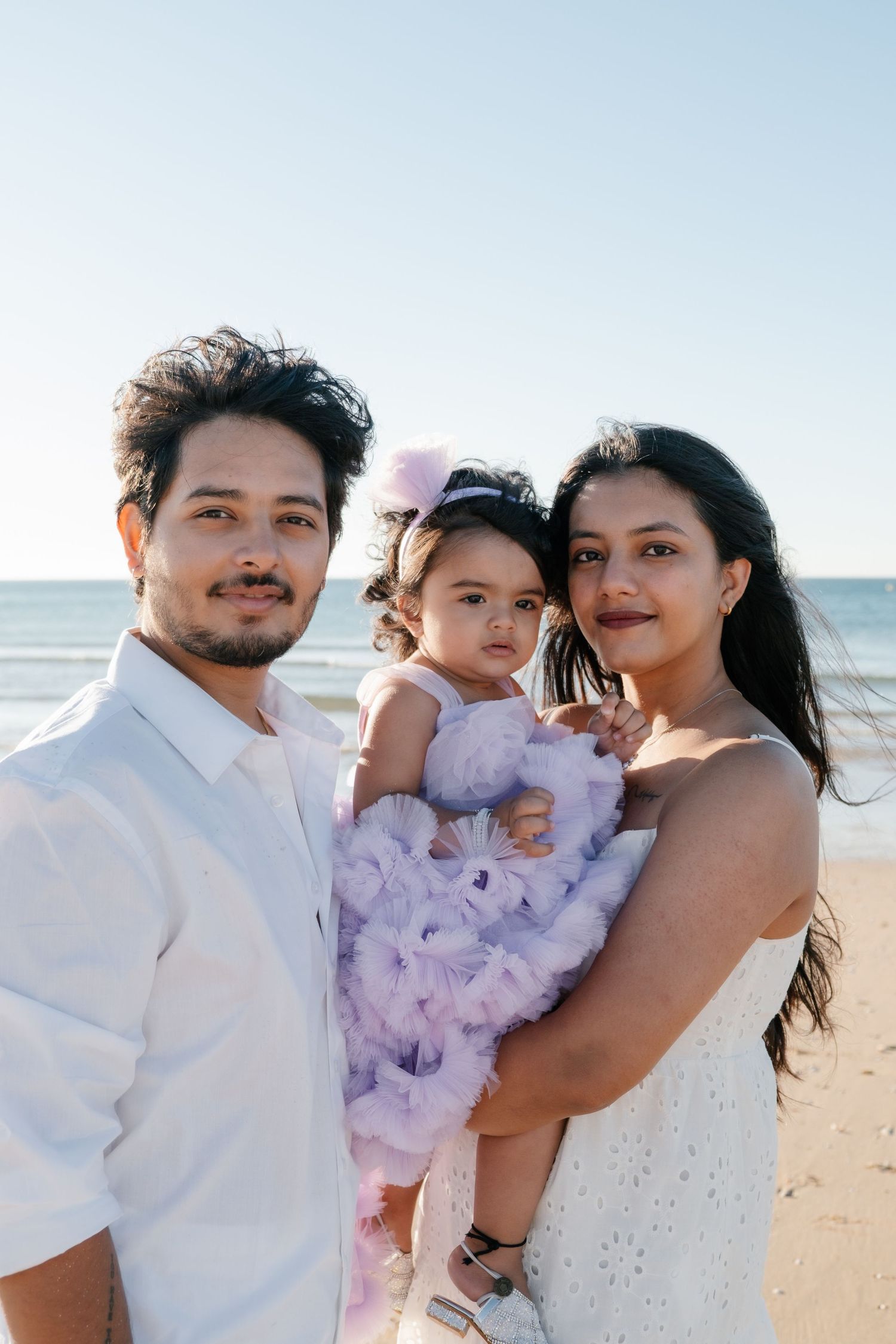 Baby with parents on the sandy shoreline at Meia Praia.