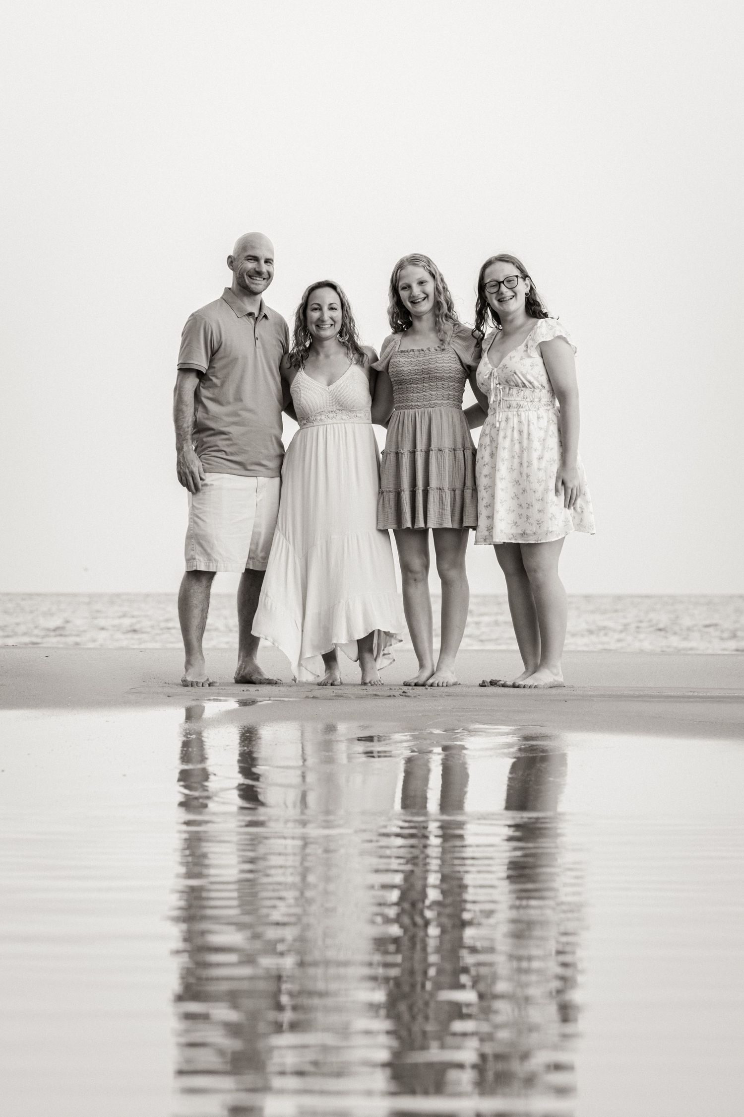 family standing together with sunset reflection in shallow pools at Porto de Mós beach