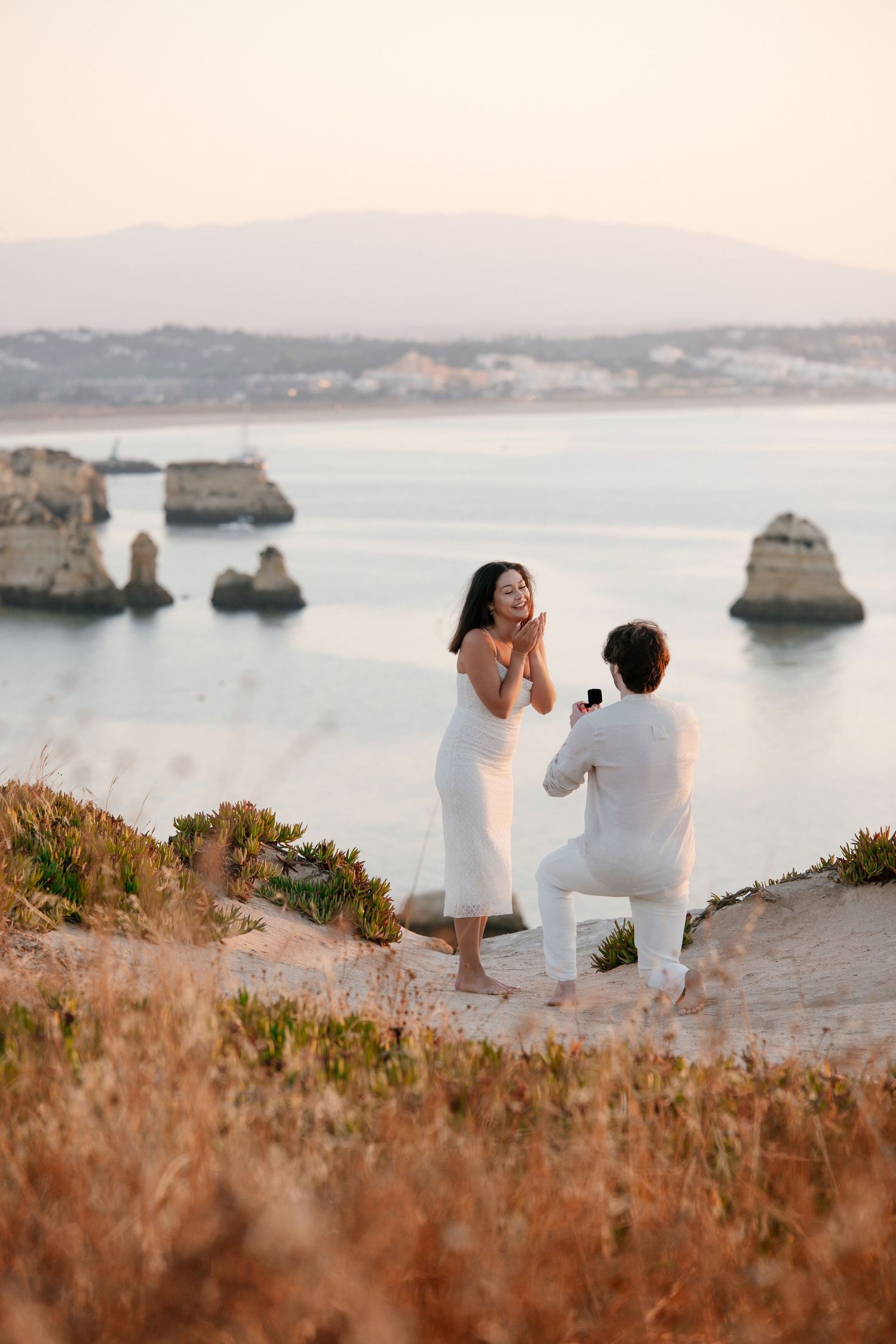 best couple proposal spot on cliffs with layered Algarve rock formations behind them at sunrise