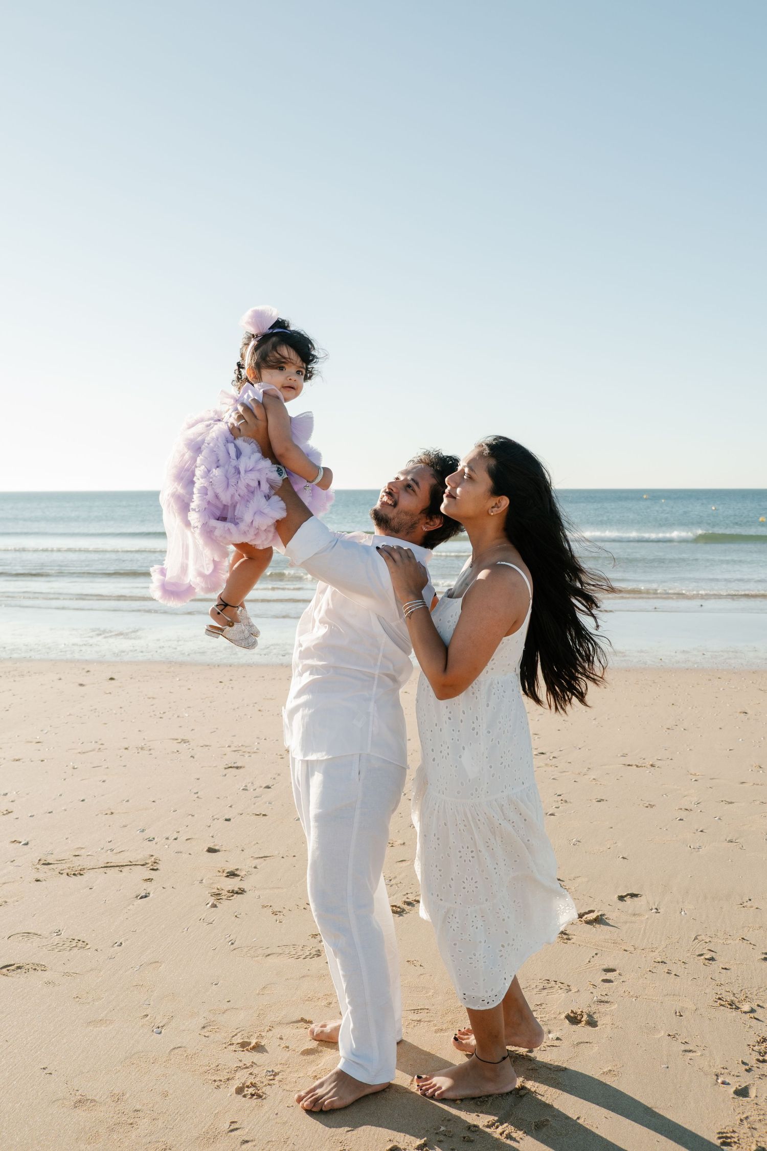 Parents lifting baby into the air and smiling to her