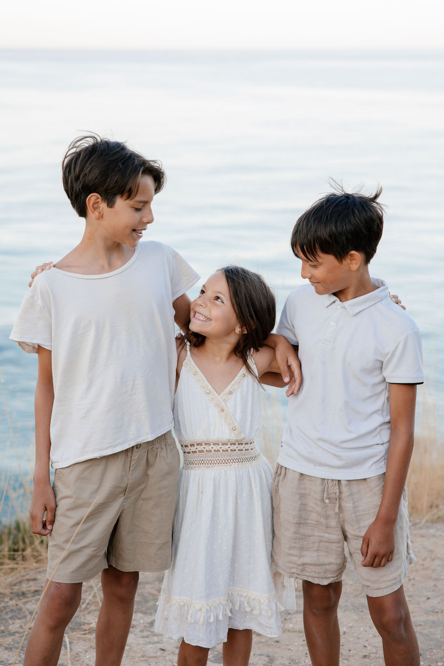 Siblings walking on windswept cliffs overlooking the Atlantic in Portugal.
