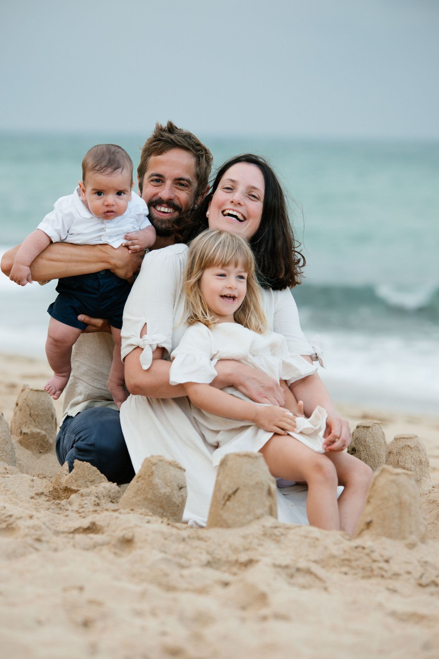 Family sitting together on the sand at sunrise on Porto Mós beach