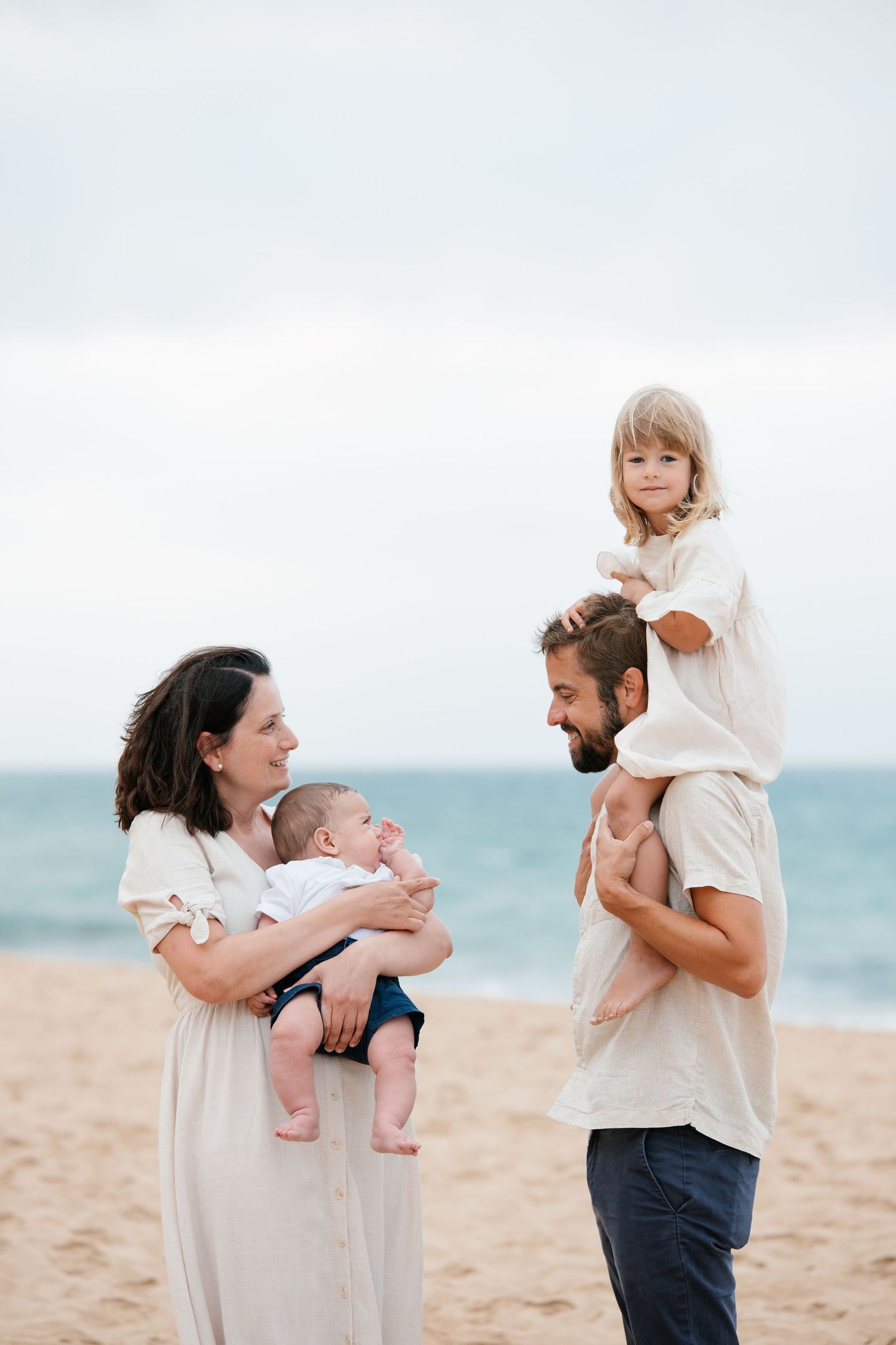 Family enjoying candid moments on sandy shoreline in Lagos, Algarve during sunrise.