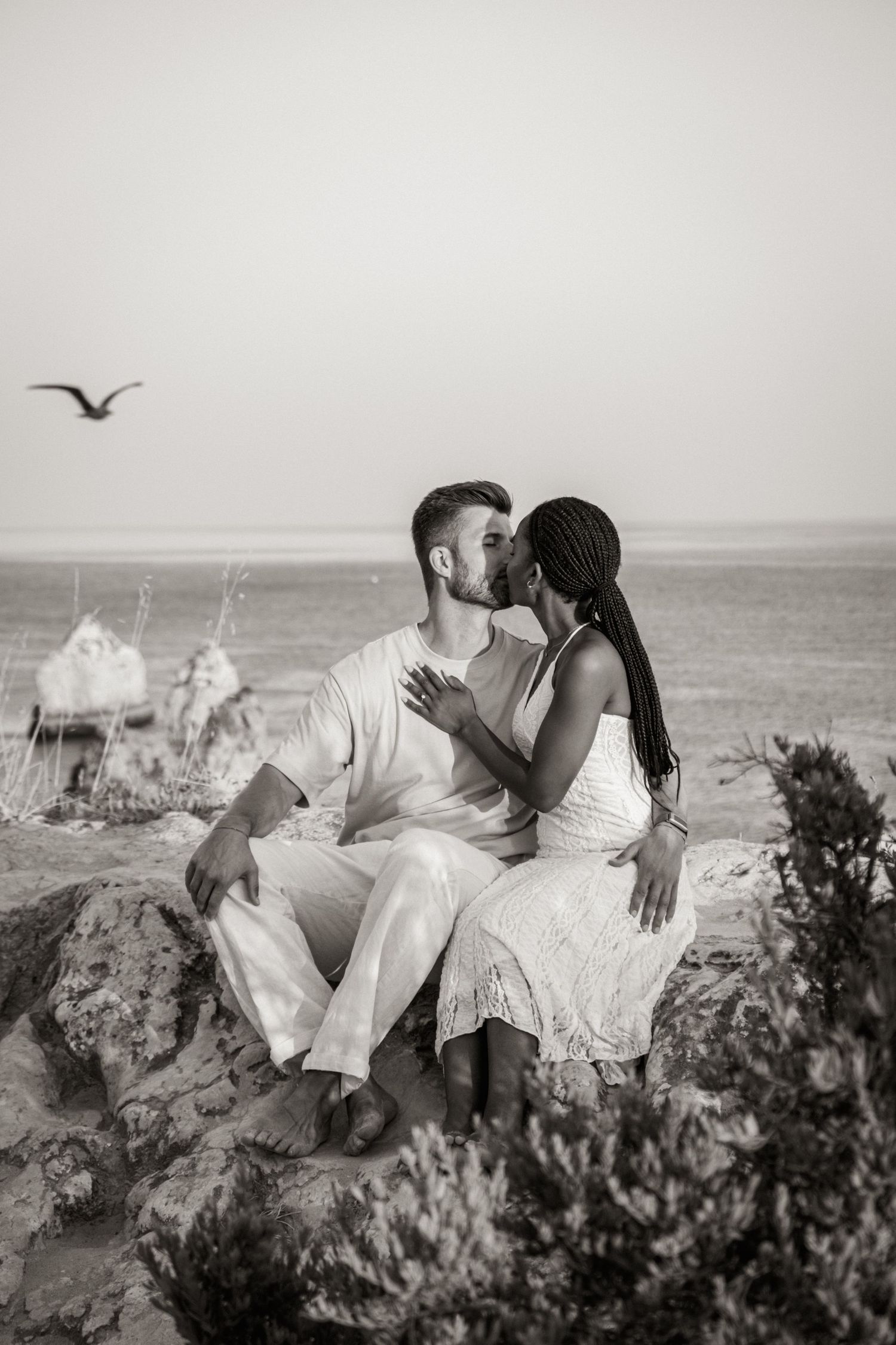 couple kiss on top of cliff with bird in background