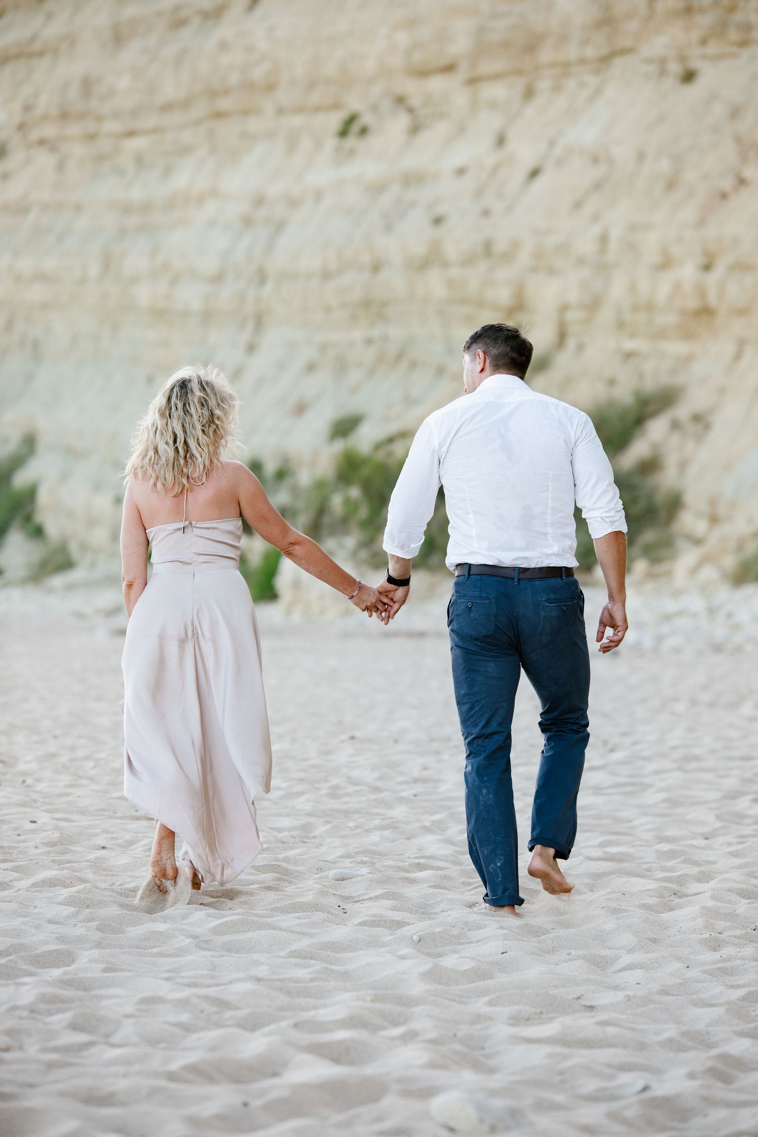 Playful couple running along the shoreline during sunset.