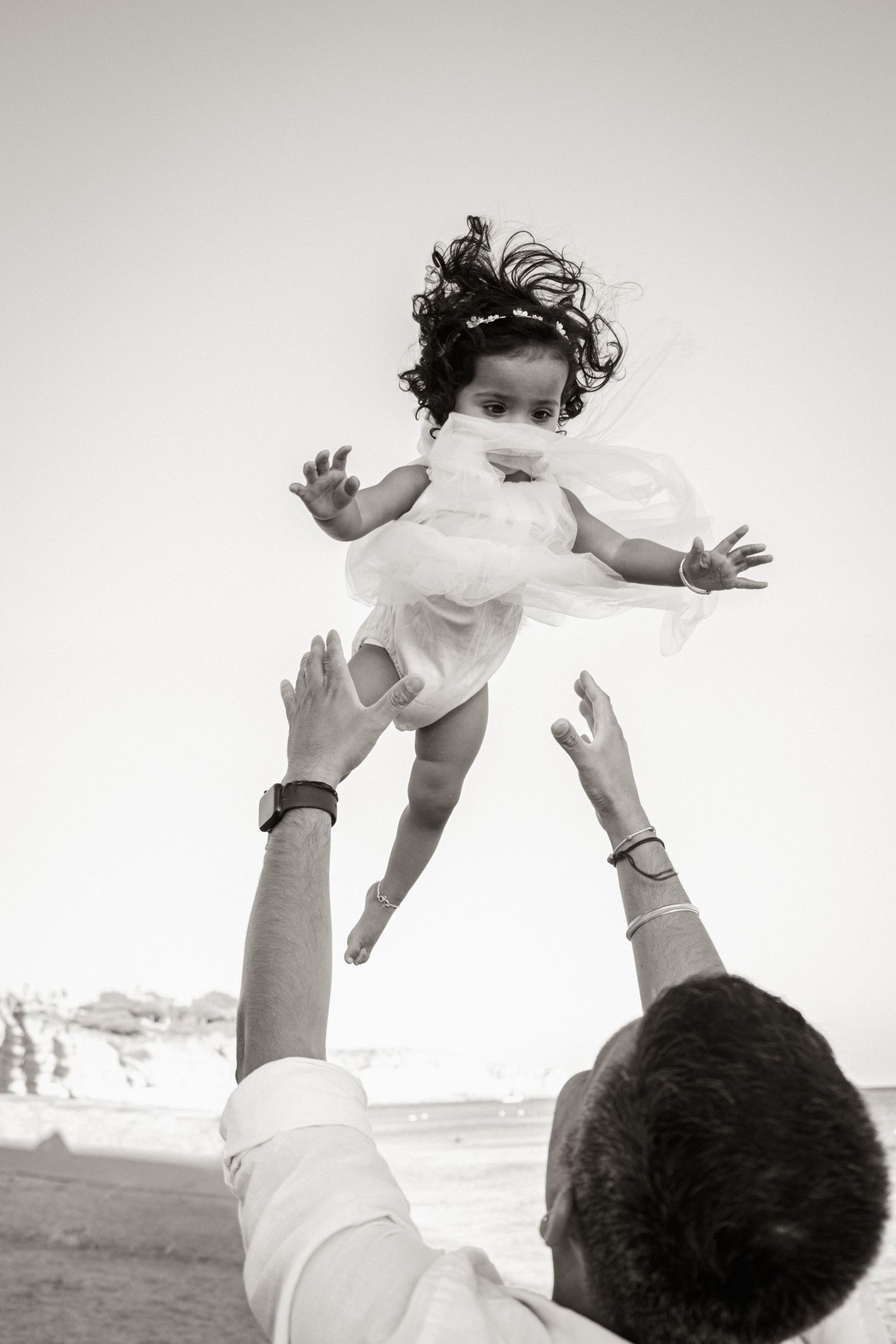 father tossing baby gently in the air during natural family session at Porto de Mós beach