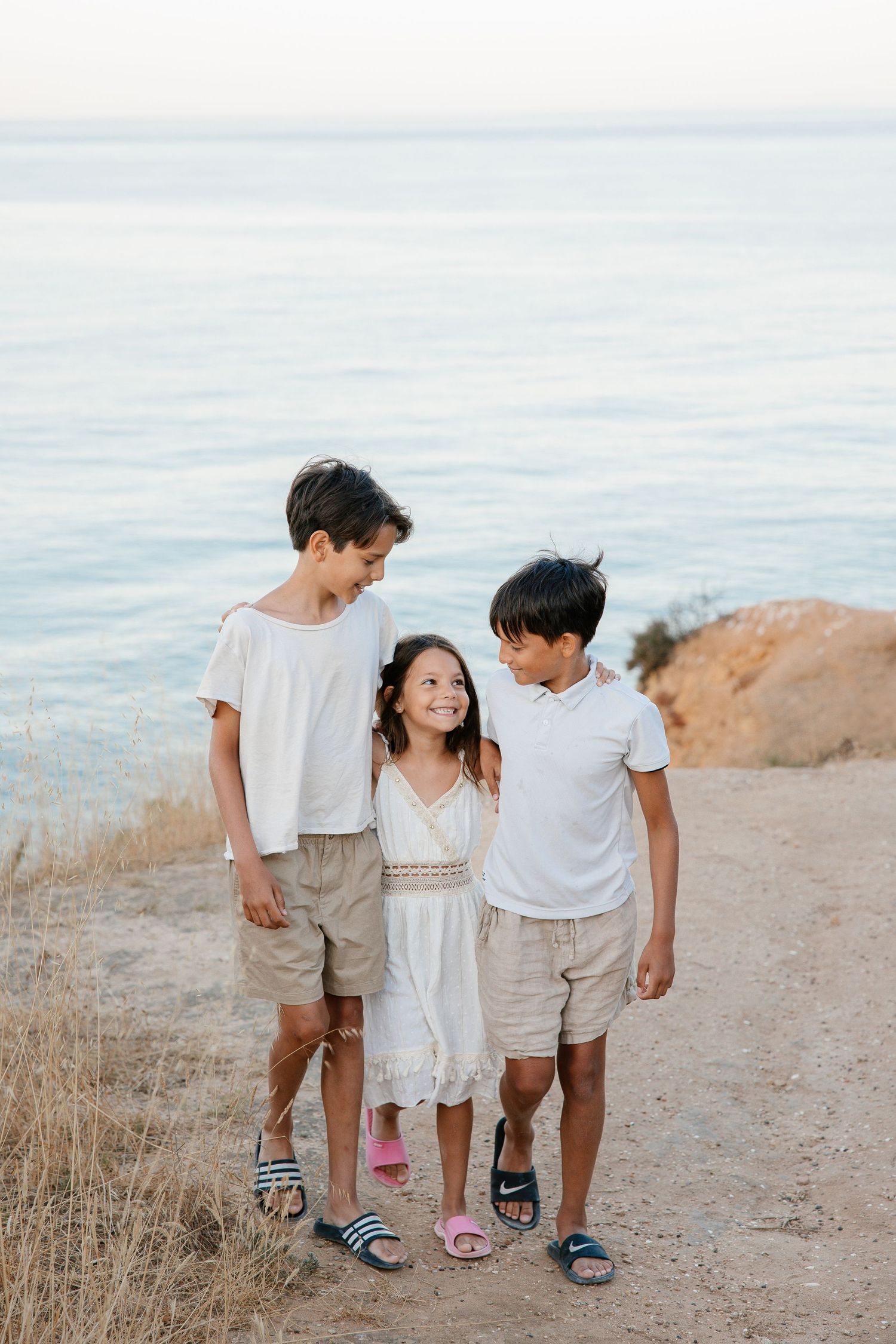 Children exploring rocky cliff paths by the sea in Portugal.