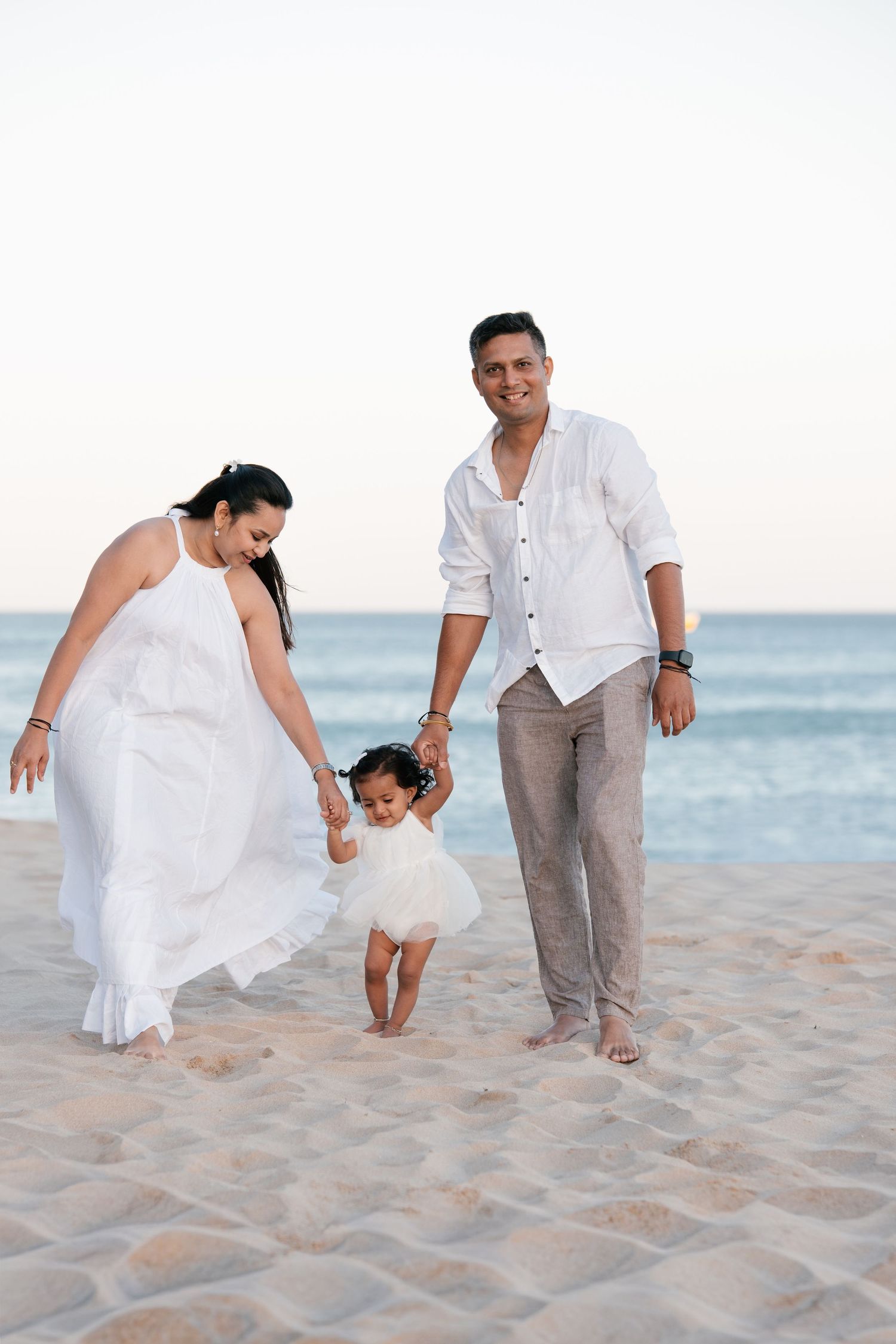 parents holding their one-year-old during a first birthday beach photoshoot in Porto de Mós Algarve