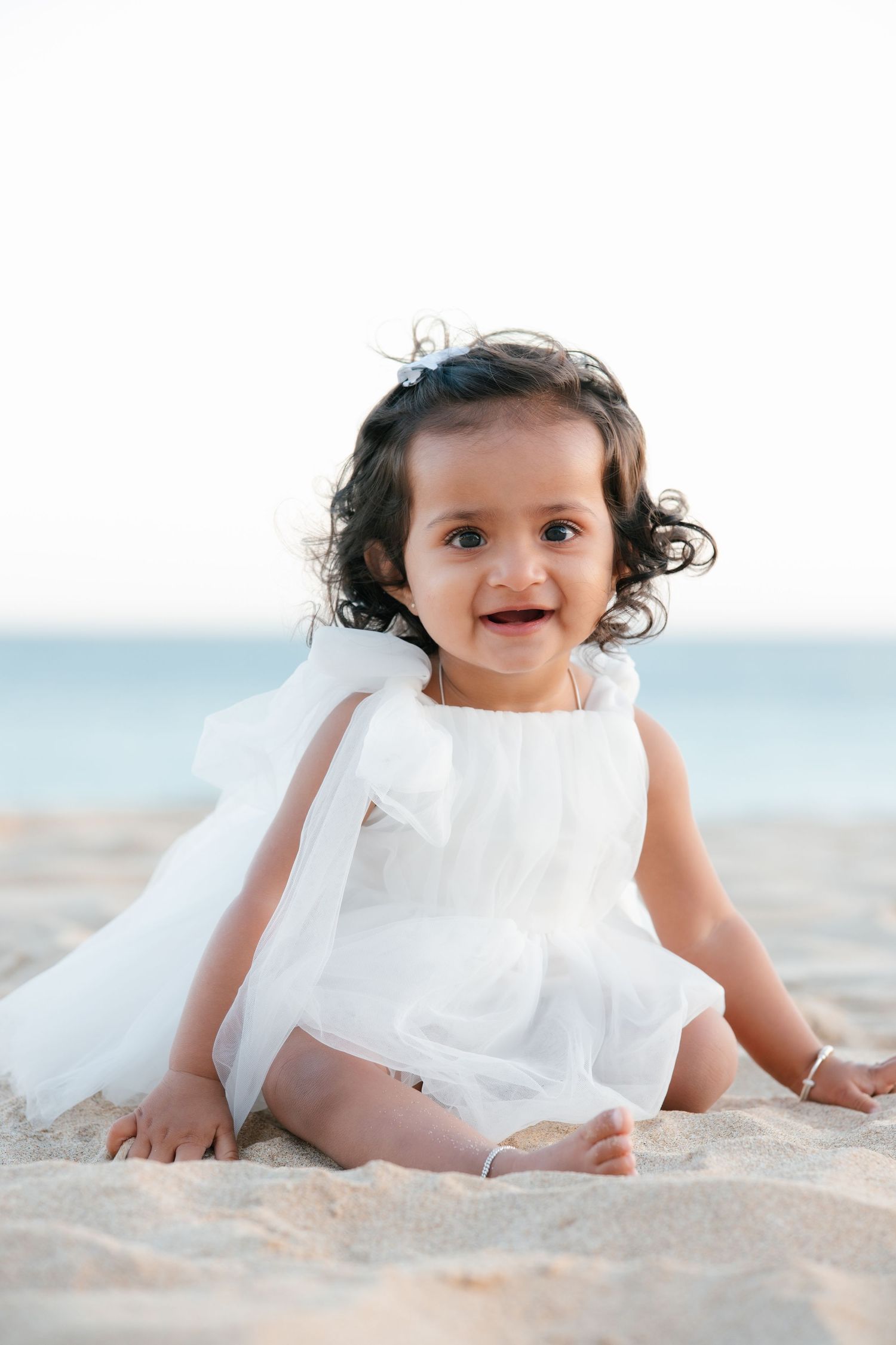 first birthday portrait of baby sitting on sandy beach in Algarve