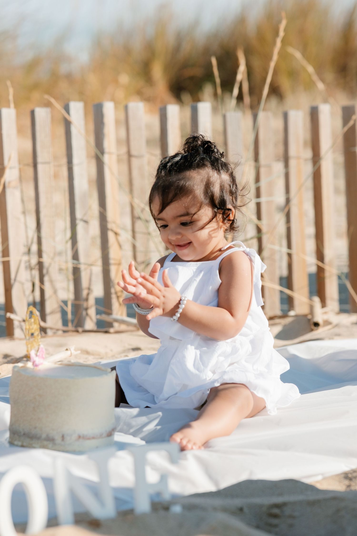 Close-up of baby’s hands cutting birthday cake at the beach.