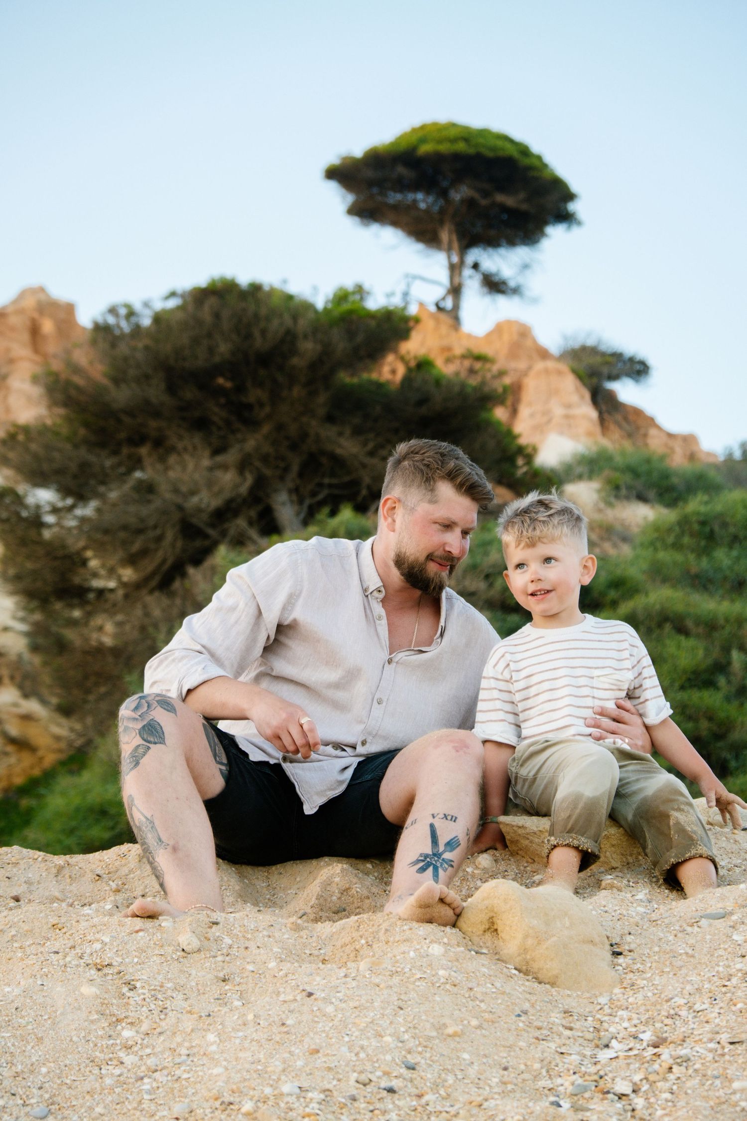 dad and son sitting in the sun hugging each other