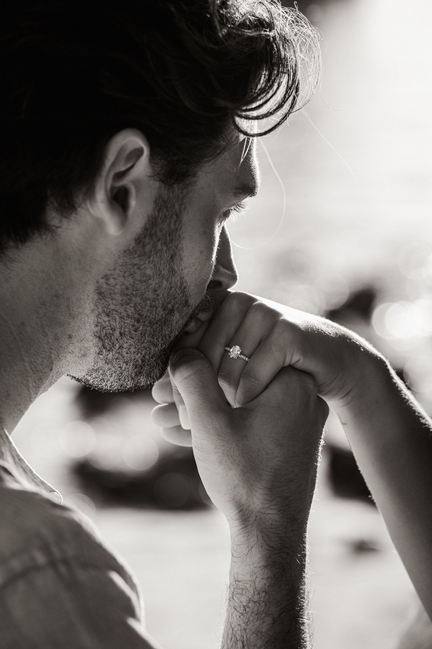 tender kiss on hand with diamond ring sparkling in soft golden light