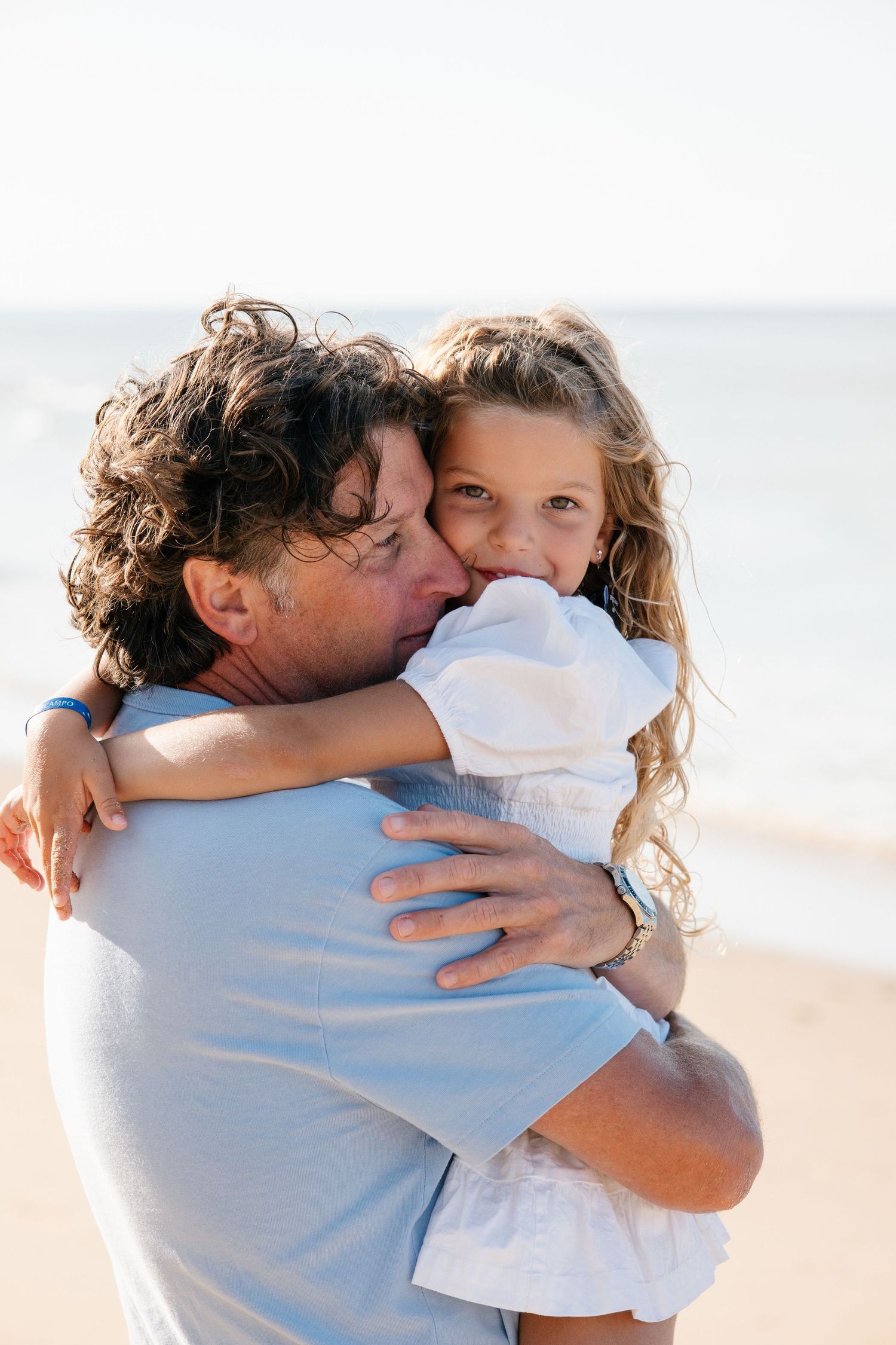 farther and daughter hugging each other on the beach