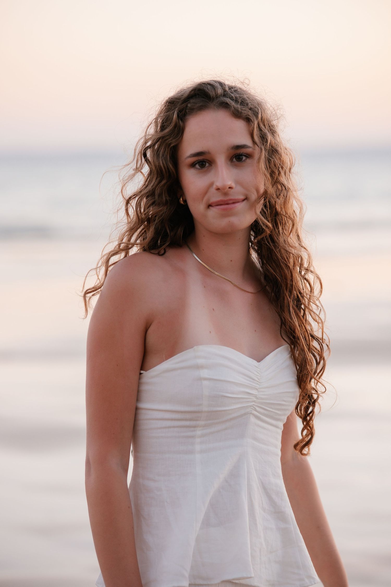 beautiful close-up portrait of girl wearing a white dress at Praia Três Irmãos during sunset