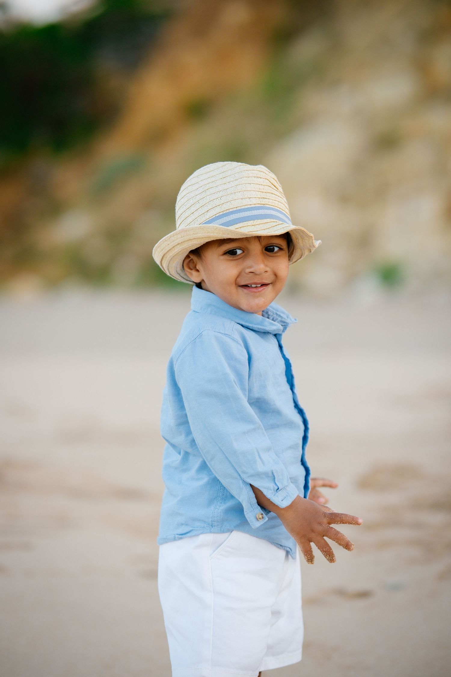 Cute little boy with a hat on standing on the beach of porto mos