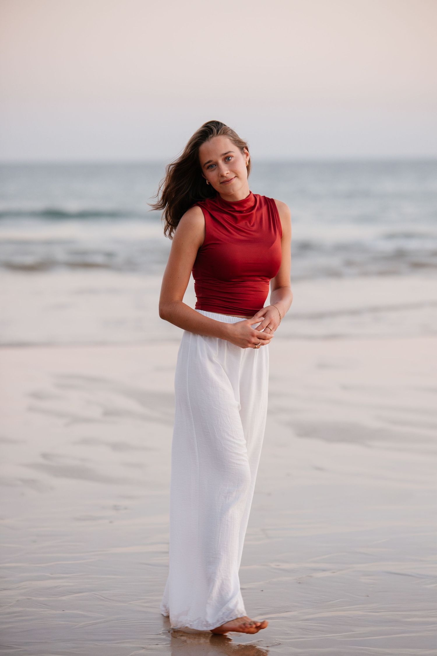 sunset beach portrait of girl on the shore at Três Irmãos wearing red top and white pants