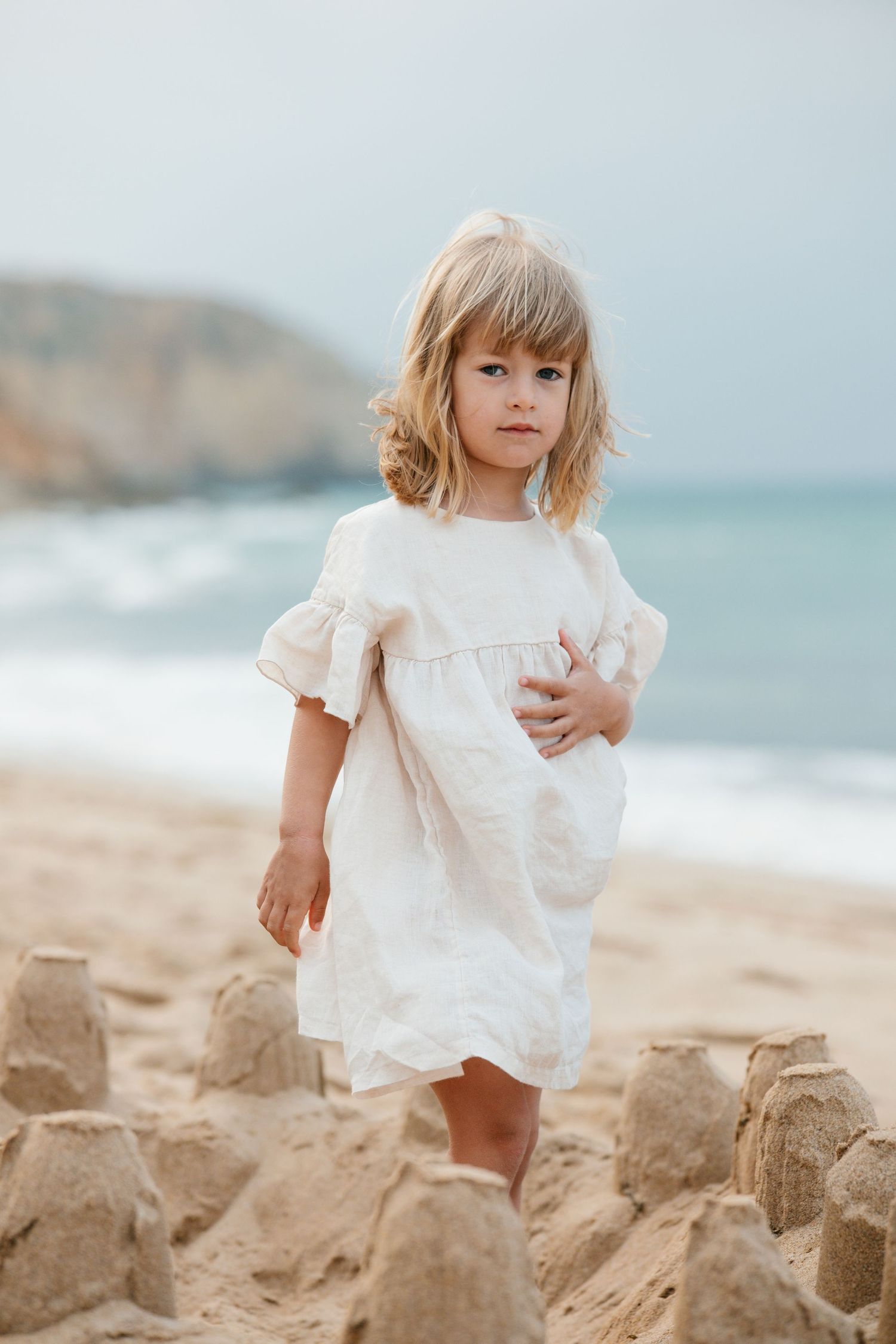 Close-up of daughter standing in a sandcastle on the beach at sunrise