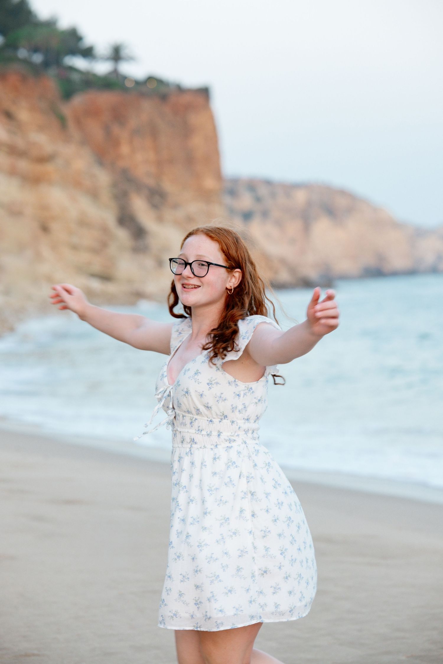 candid portrait of daughter smiling at something off-camera with cliffs in the background