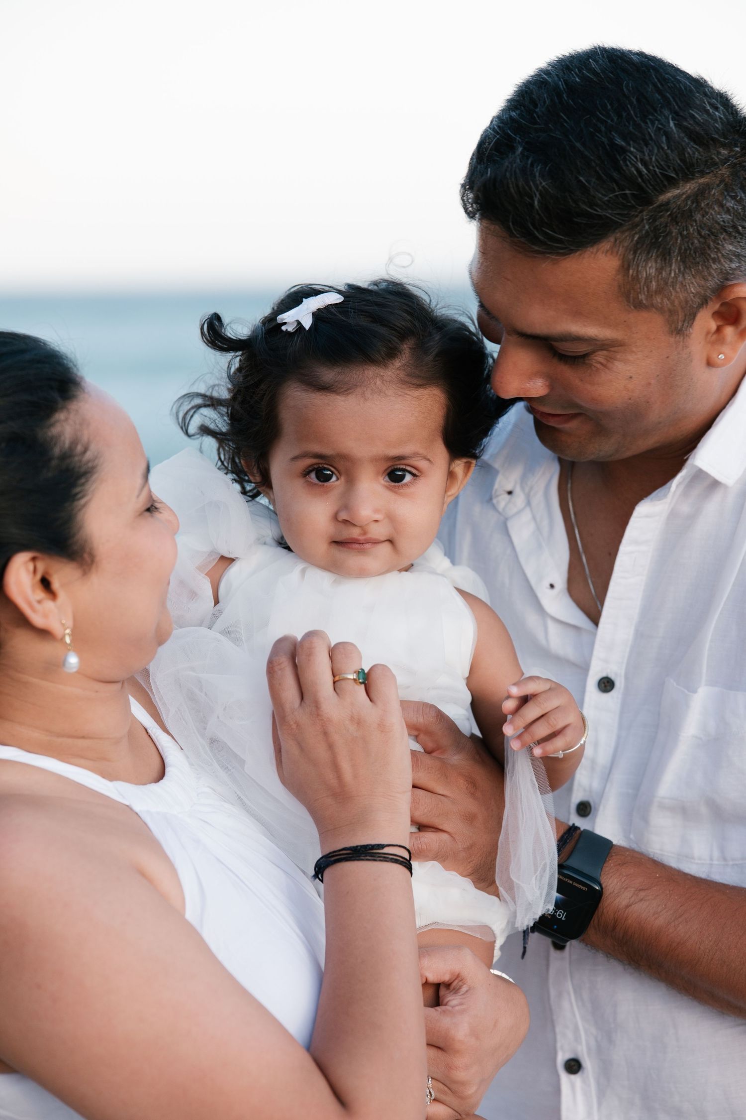 close-up of parents kissing their one-year-old at Porto de Mós beach during sunset