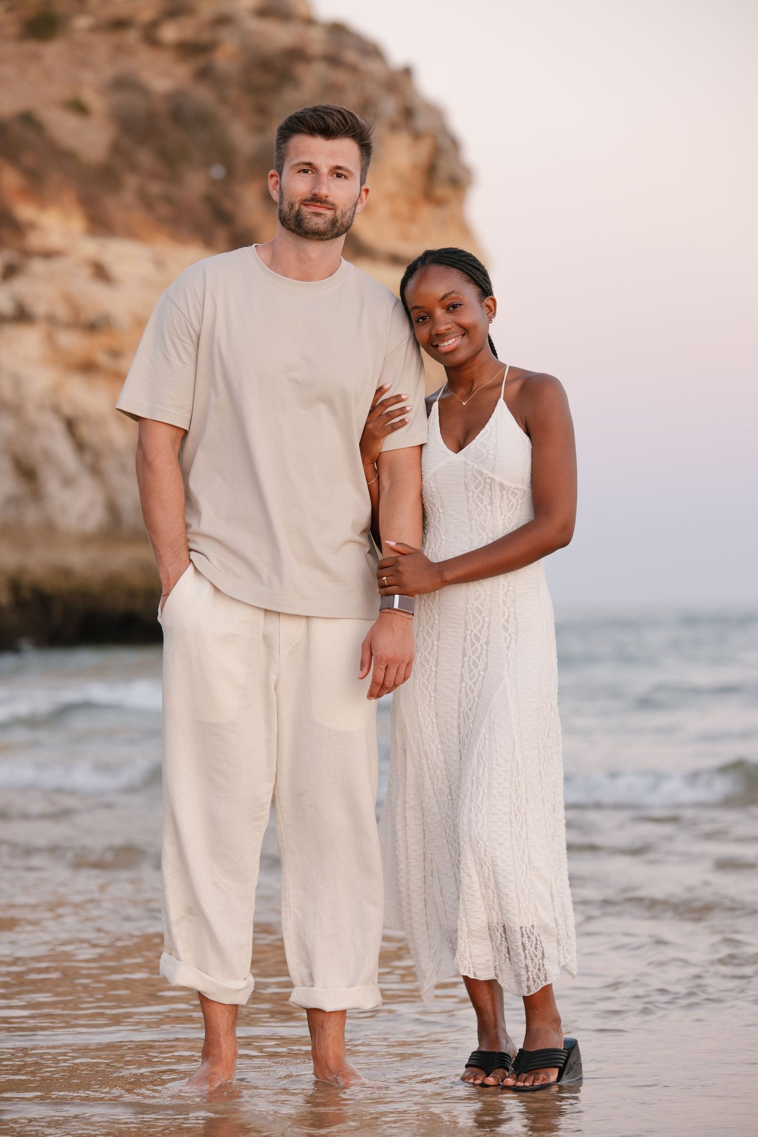couple hugging each other, woman takes the arm of the man. With the cliffs on the beackground