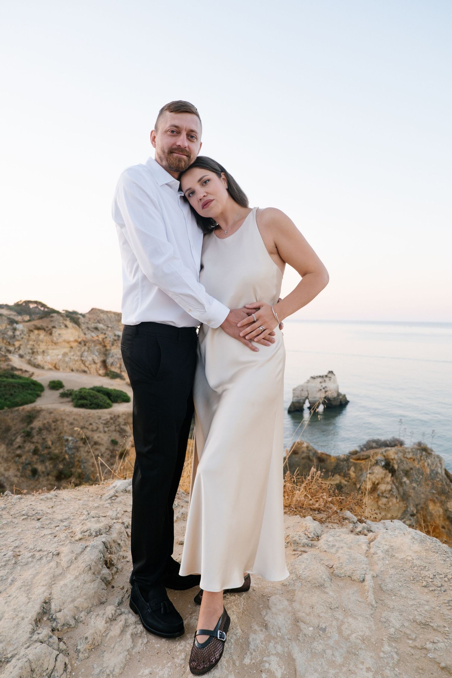 cozy couple wrapped in arms on Algarve cliffs with soft morning light