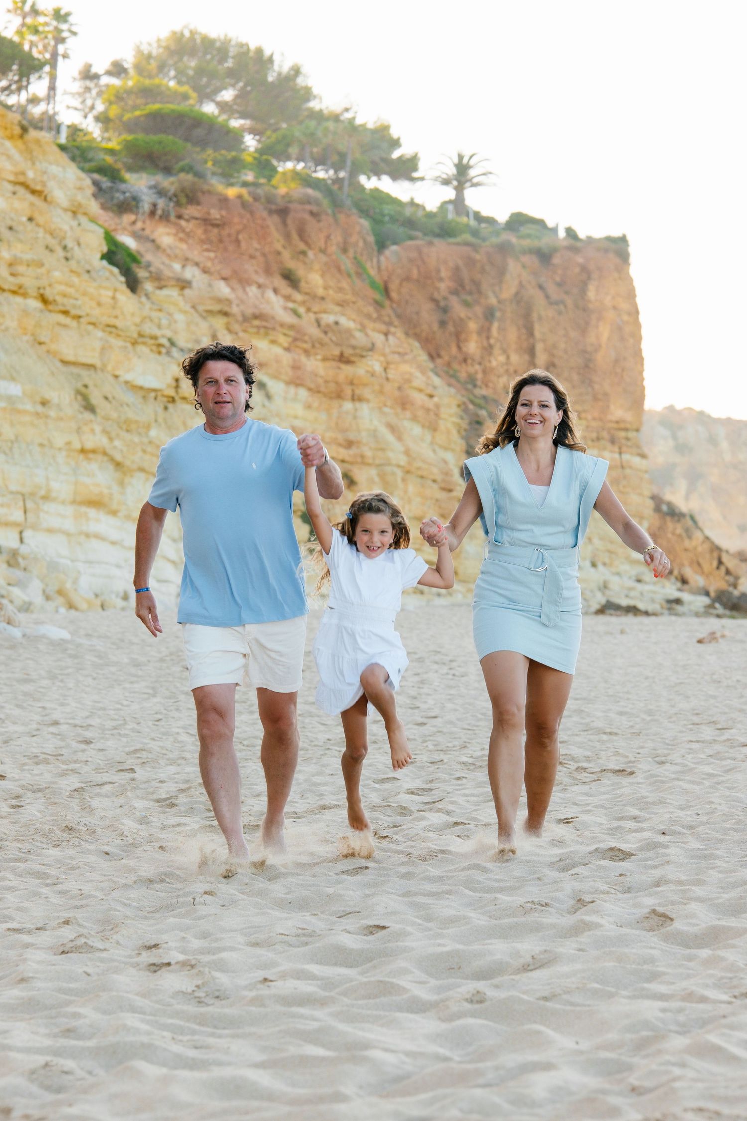 family walking on the sand with cliffs on the background on algarve stunning beach