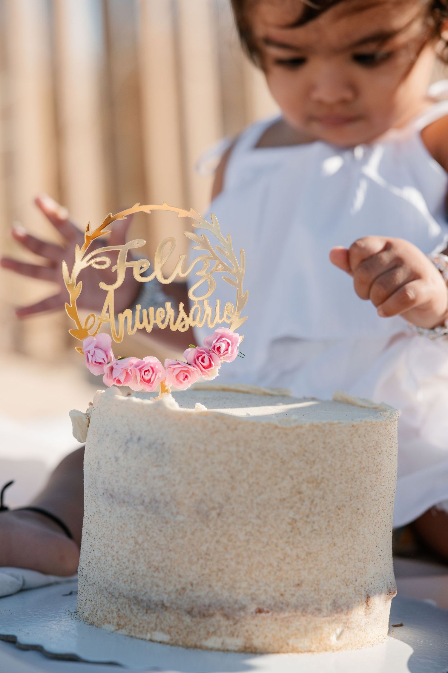 Baby cutting birthday cake on the sand during first birthday beach session.
