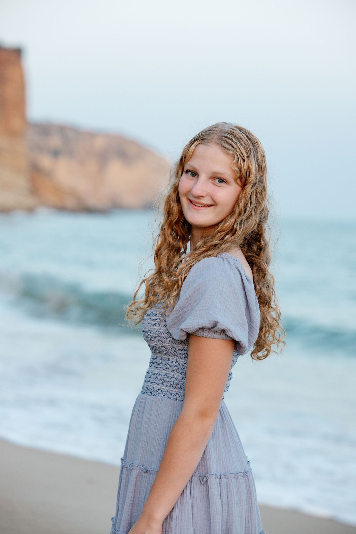 close-up portrait of daughter smiling at Praia Porto de Mós during sunset