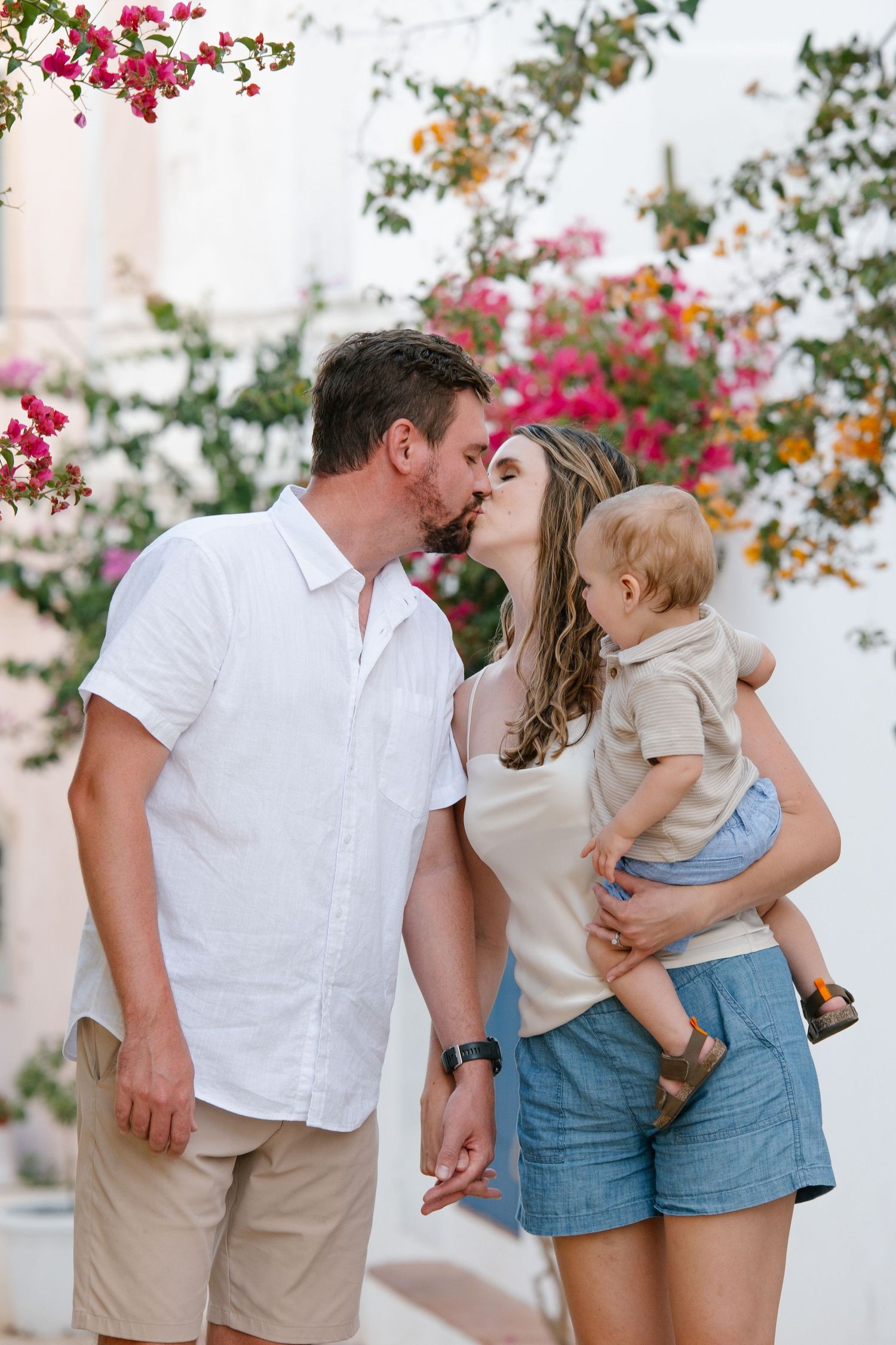 candid family moment in a narrow Lagos alley with colorful flowers and whitewashed homes