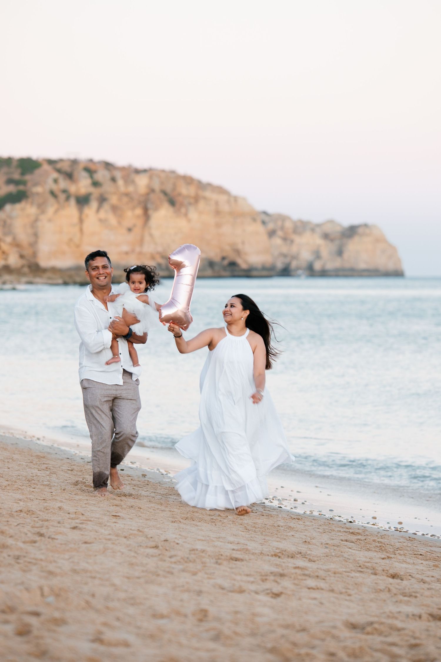 family celebrating their baby’s first birthday on Praia Porto de Mós with cliffs in the background