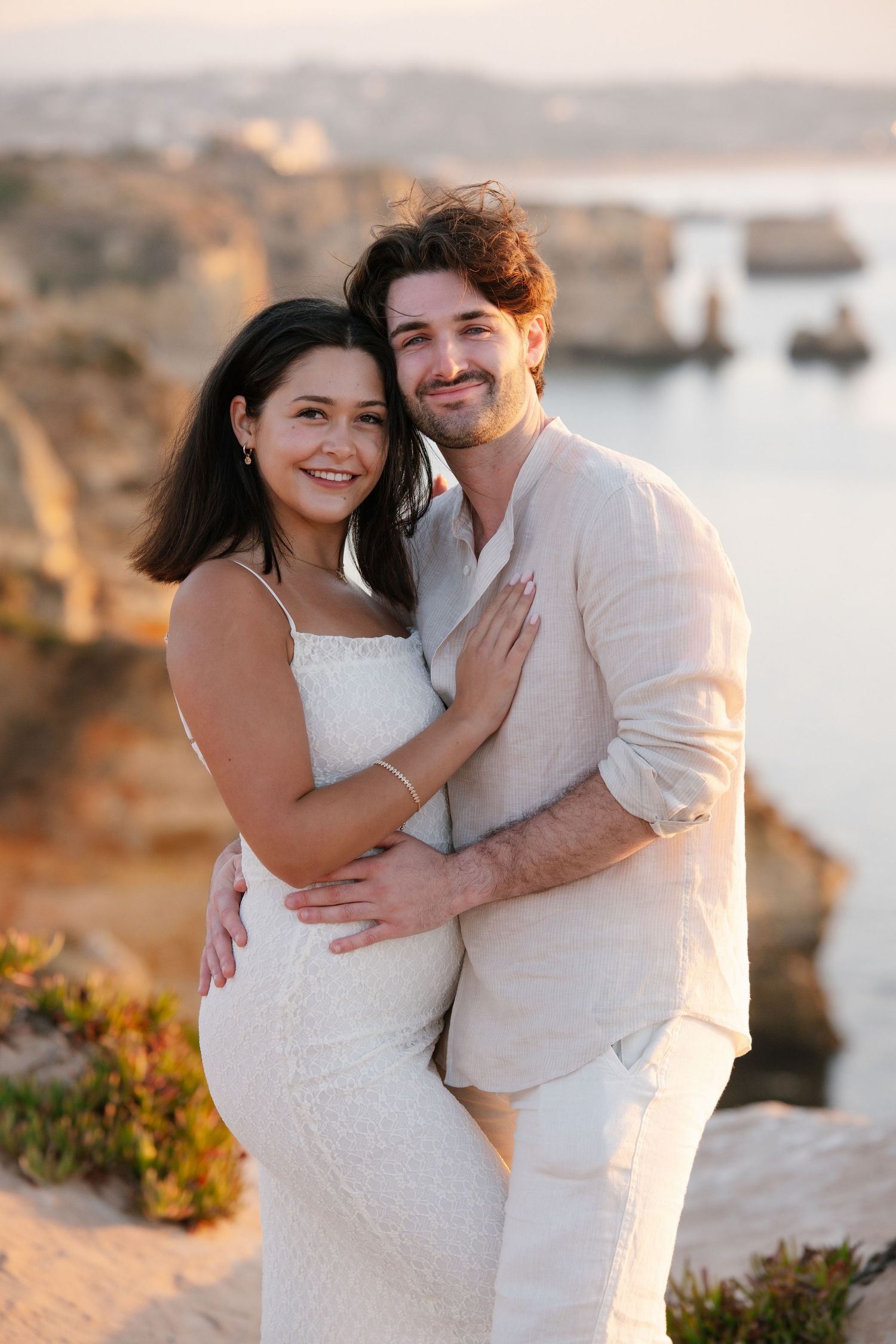 sunrise proposal with couple standing on cliff edges at Praia da Camilo with ocean views