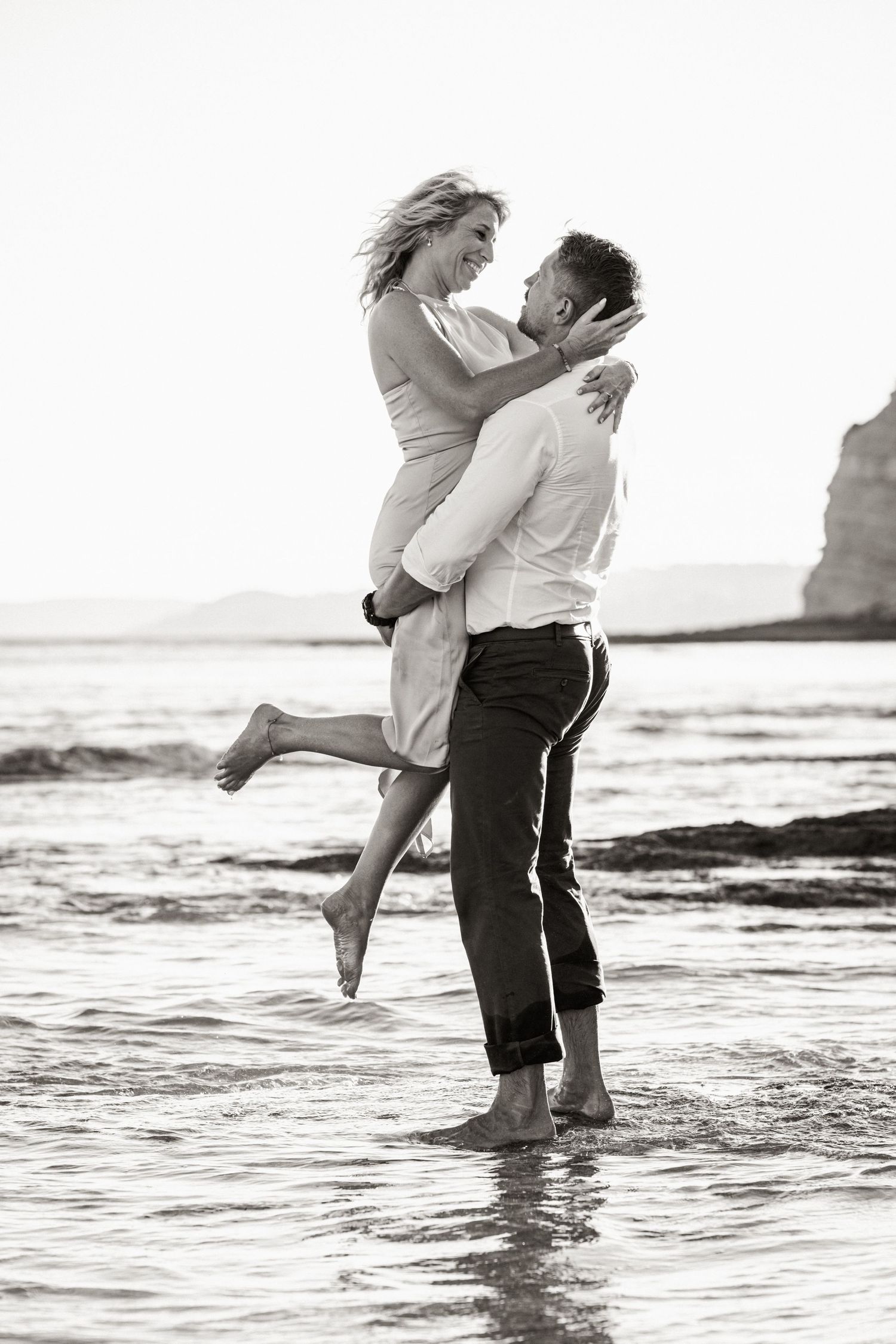 Romantic silhouette of couple holding each other with ocean horizon behind.
