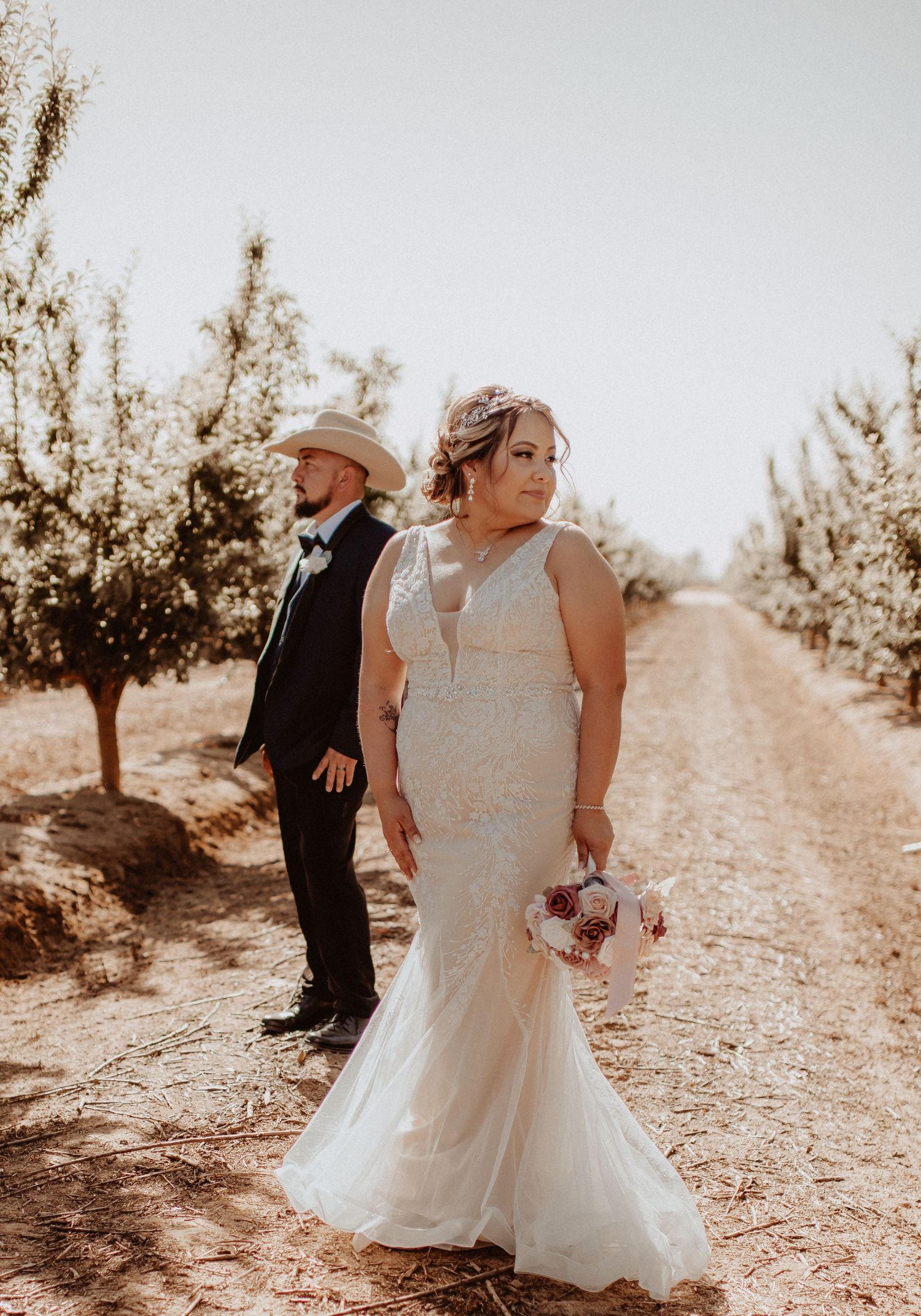 wedding couple bride in white dress in orchards looking away near Reedley, California