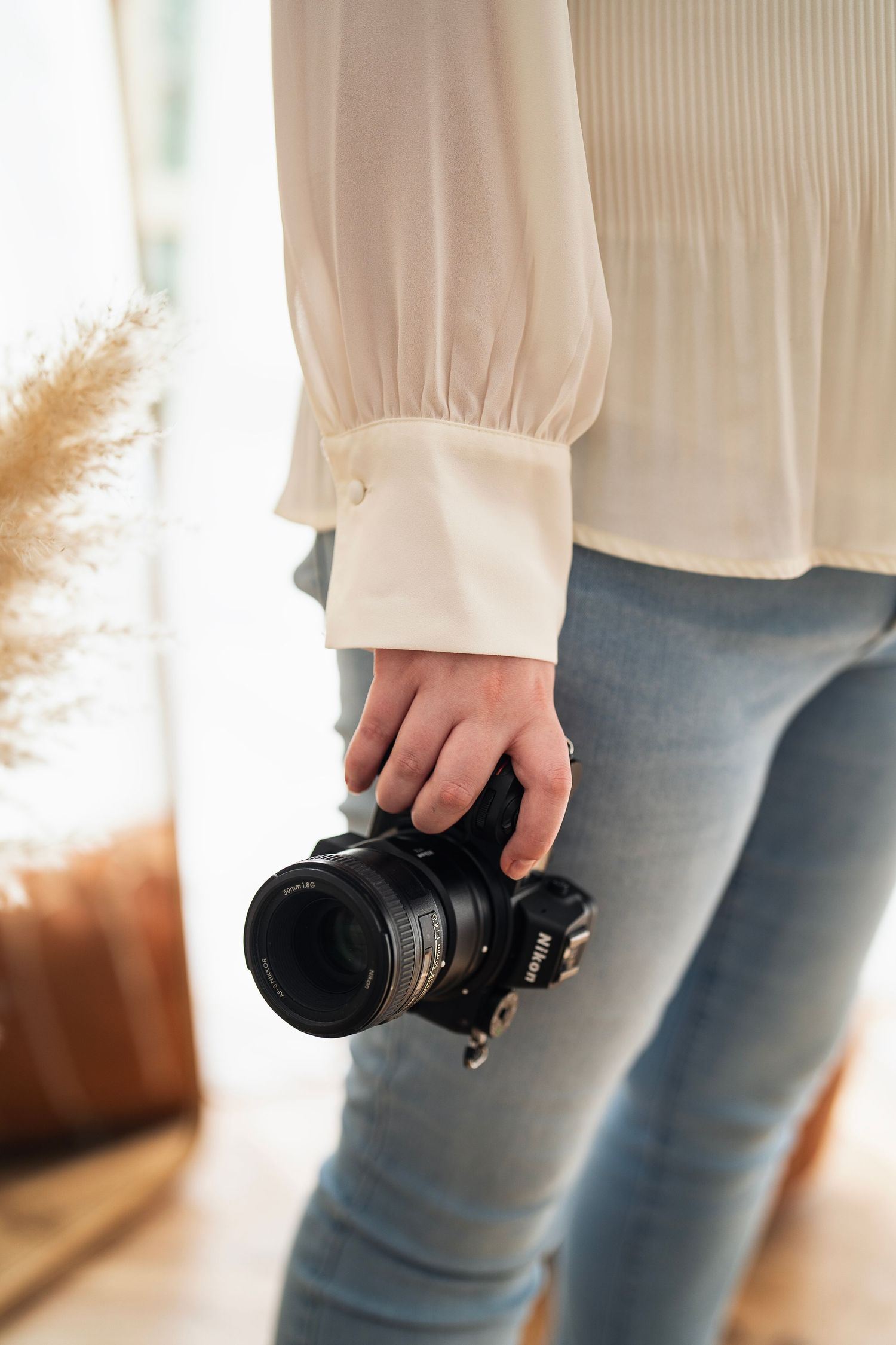 Westerville photographer ready for a session, camera in hand and light streaming through cozy studio windows.