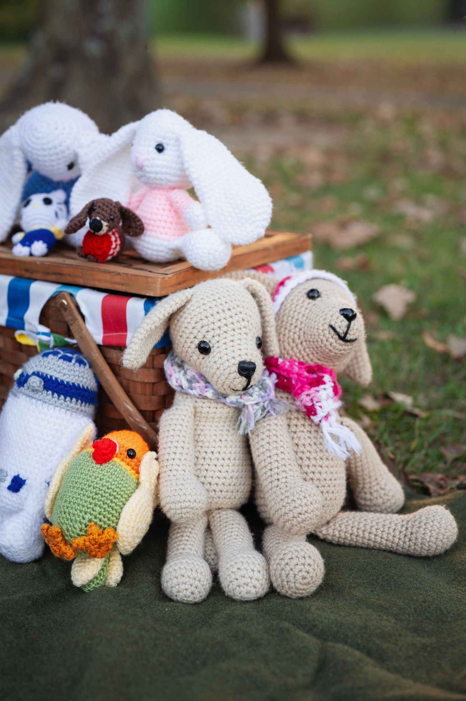 Hand-crocheted animal stuffies arranged by a picnic basket on a blanket, ready for a whimsical family photo session