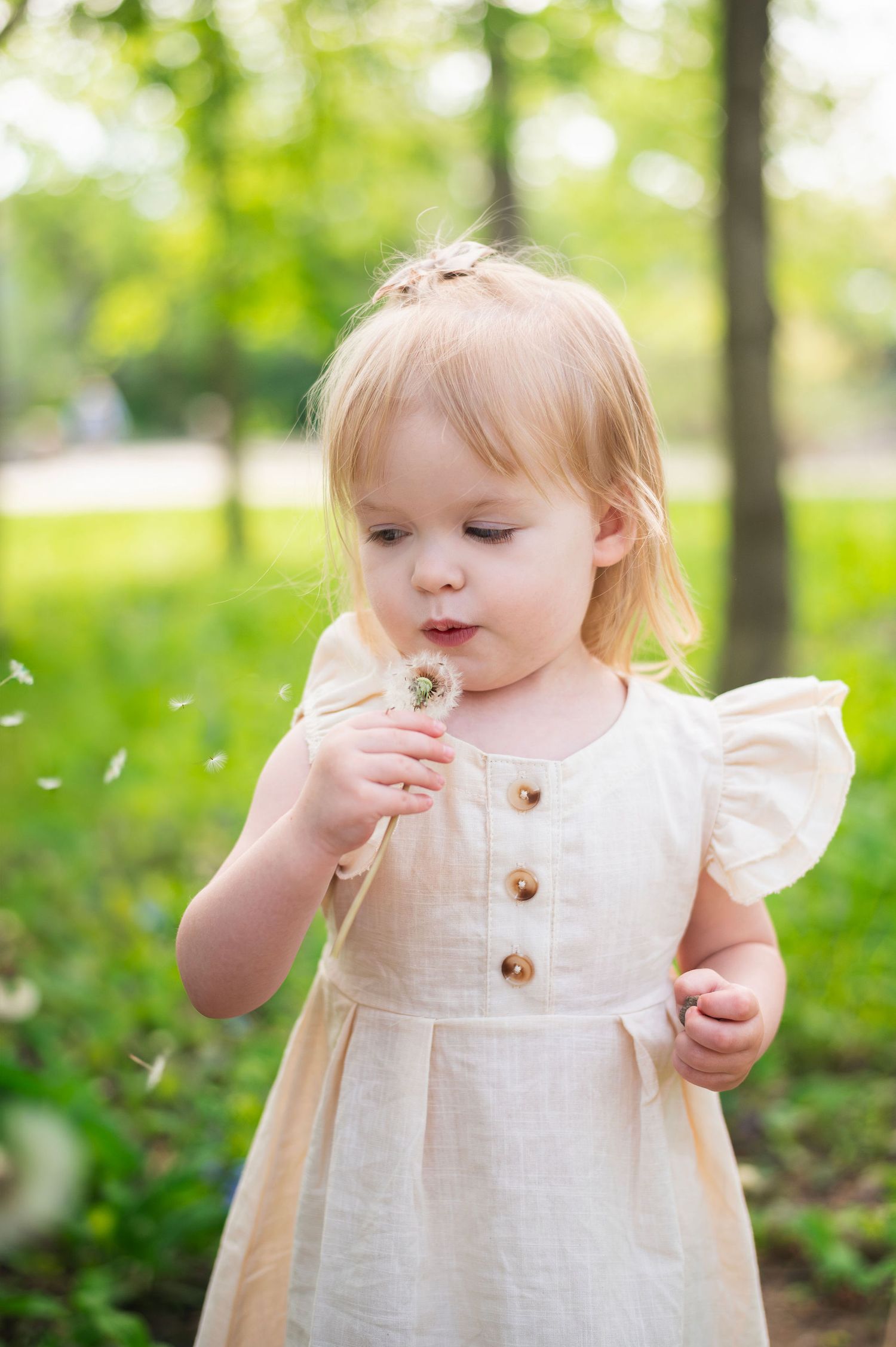 Milestone session: A little girl making a wish in a sunny Gahanna park. Childhood magic captured in one breath.