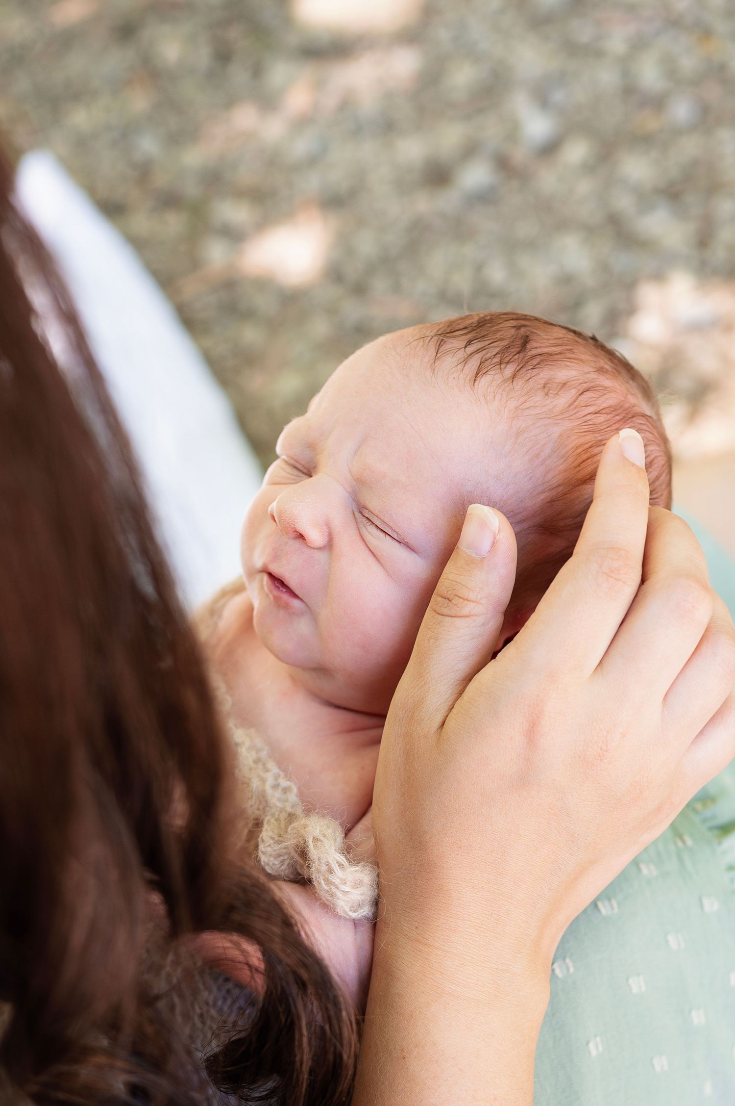 A tender newborn moment captured outdoors as baby rests in mama’s arms—natural, emotive family photography in Gahanna.