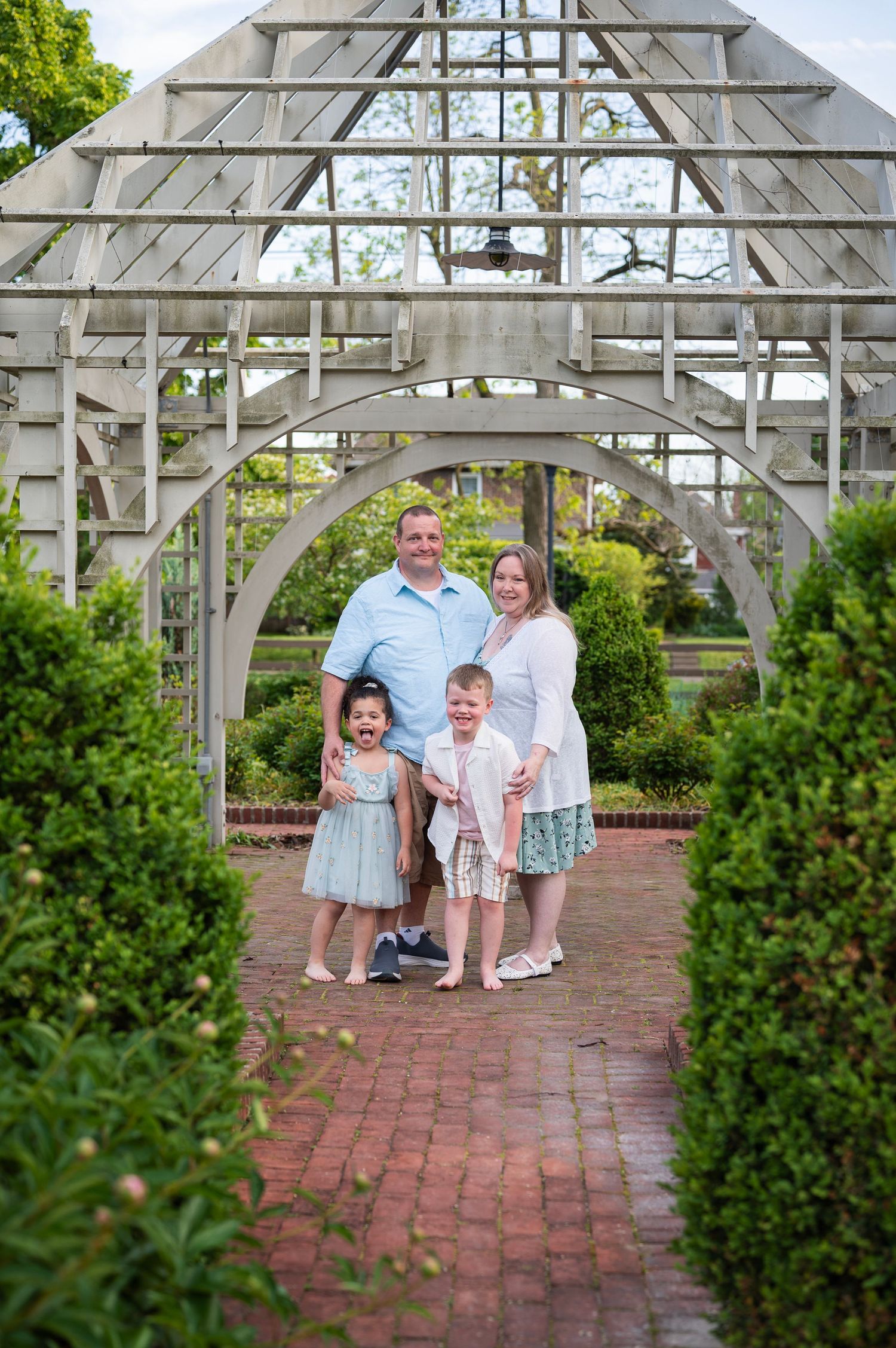 Family of four smiling under white garden arch at Franklin Park in Columbus.