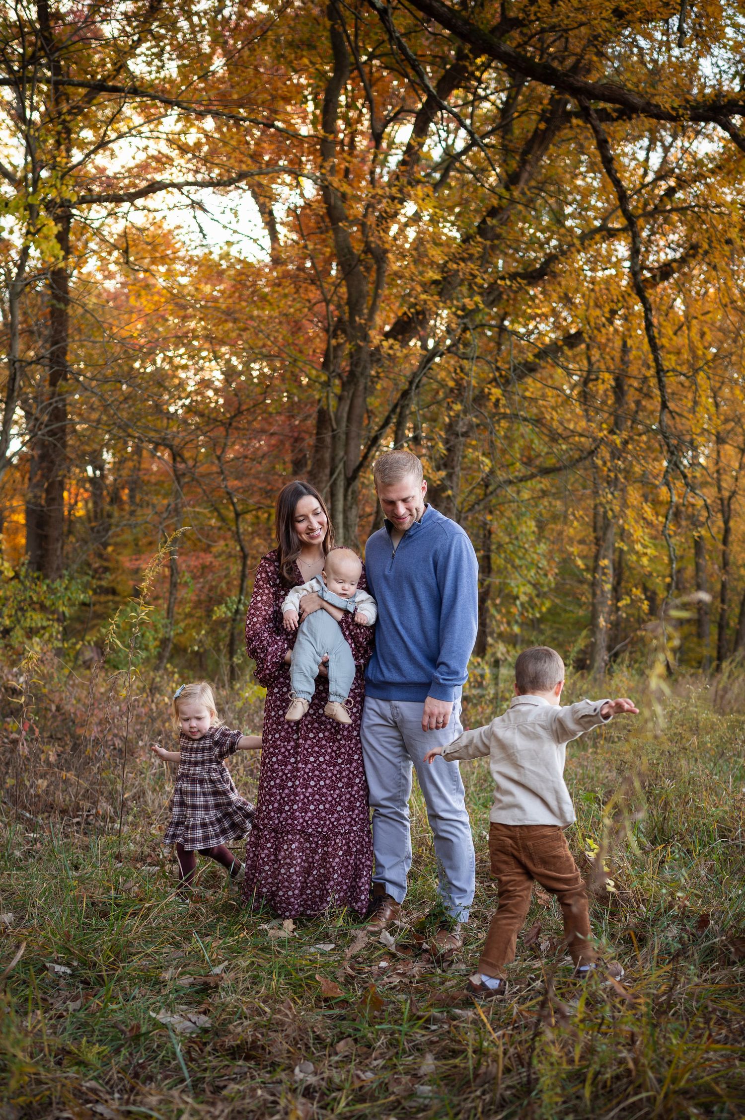 Family of five in coordinated outfits walking through a fall field during a lifestyle family photo session in Westerville, Ohio.
