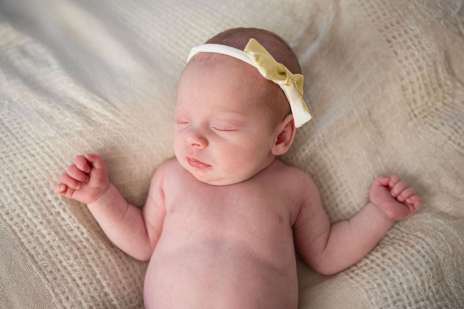 Wrapped in soft light and a yellow bow, this newborn girl brings sunshine to a newborn photography session with Boundless Joy.