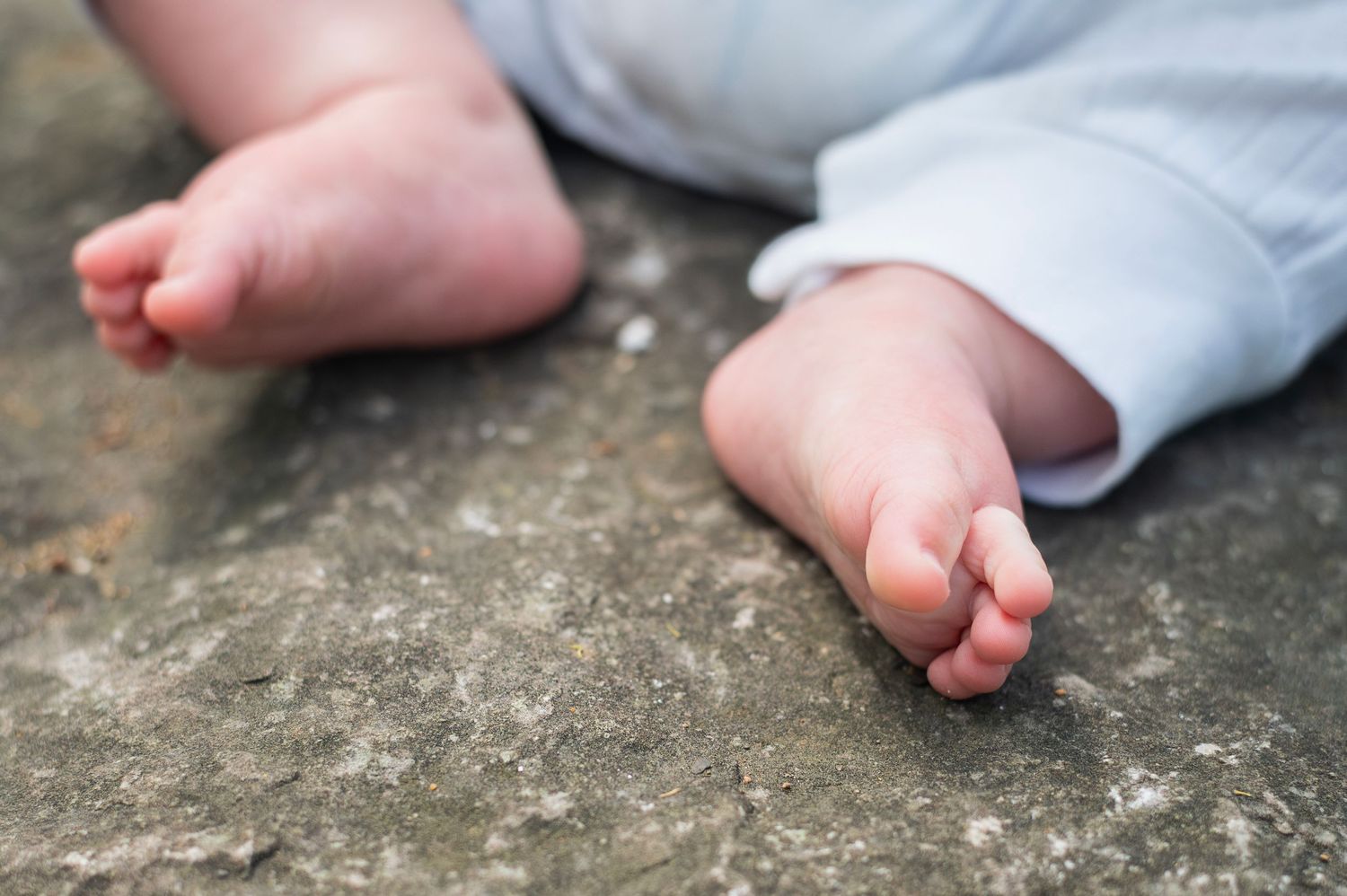 Close-up of tiny baby toes resting on a rock during an outdoor family photo session.