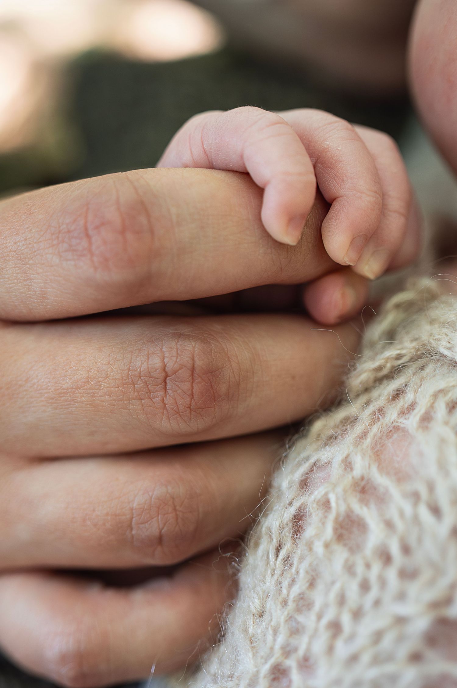 Close-up of a newborn’s hand gently gripping an adult’s finger.