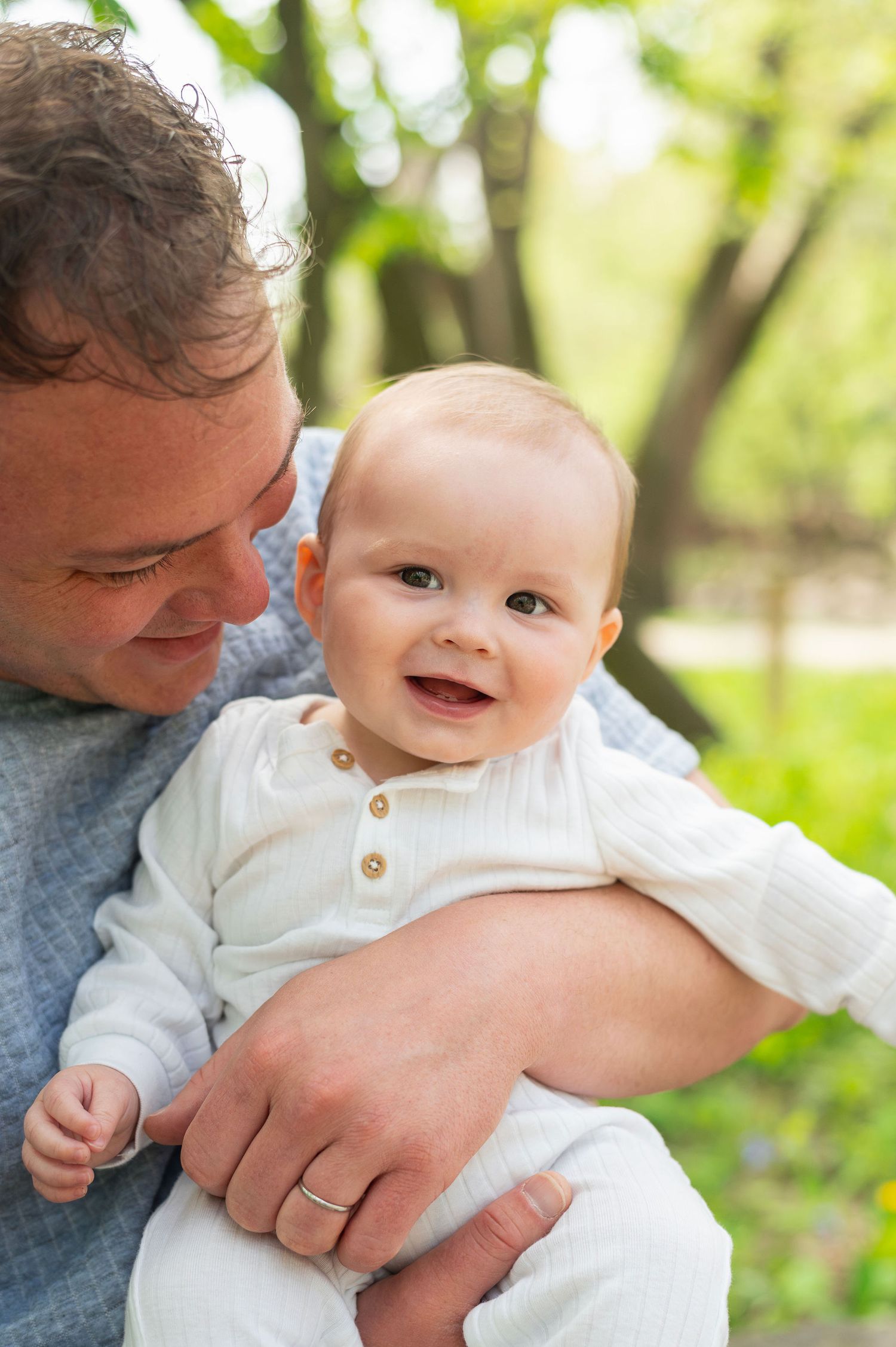 Milestone baby portrait featuring a proud dad holding his smiling baby boy—heartfelt storytelling in natural outdoor light.