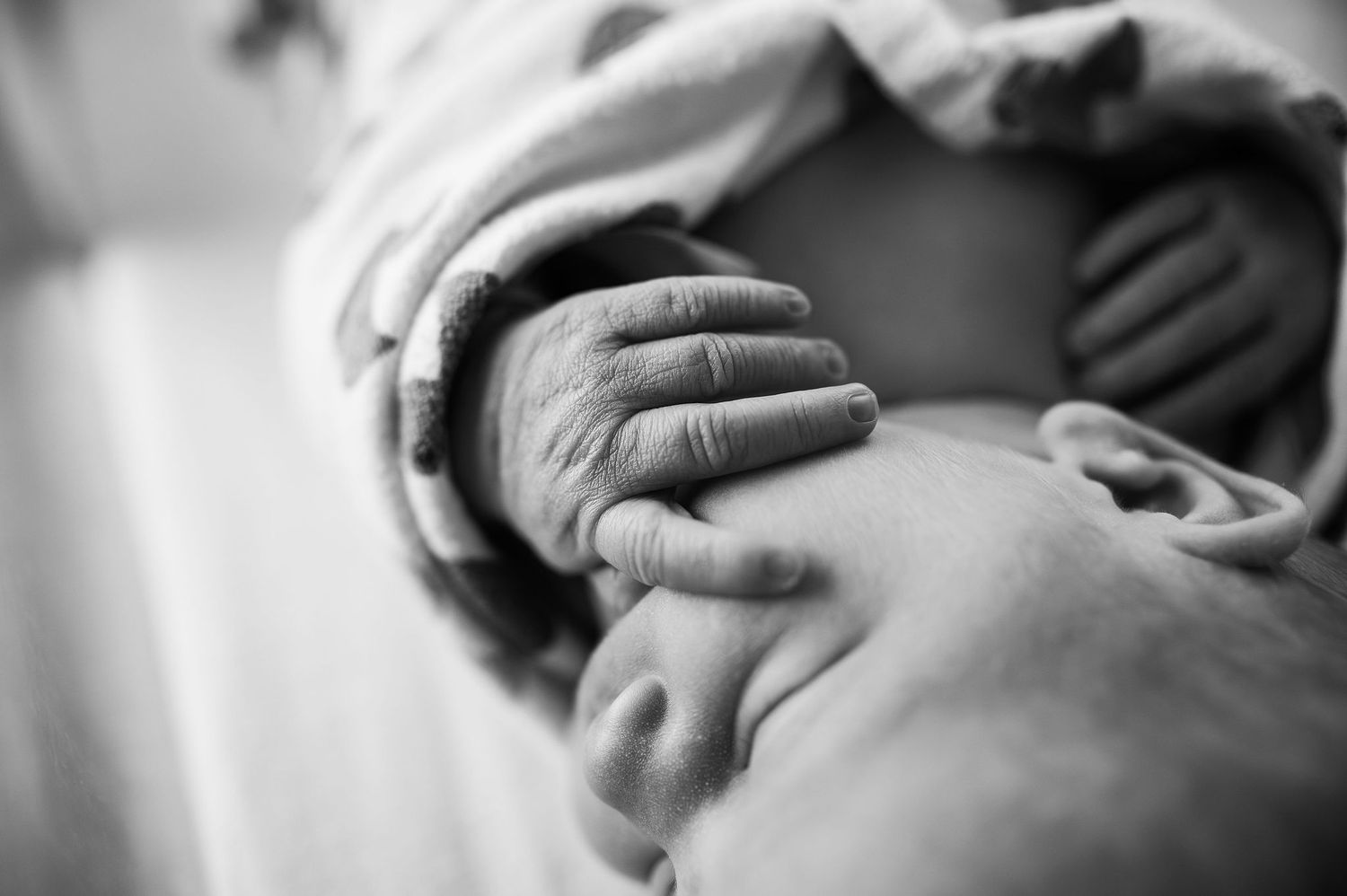 Black and white photo of newborn hand resting on parent—Fresh 48 newborn session in Westerville