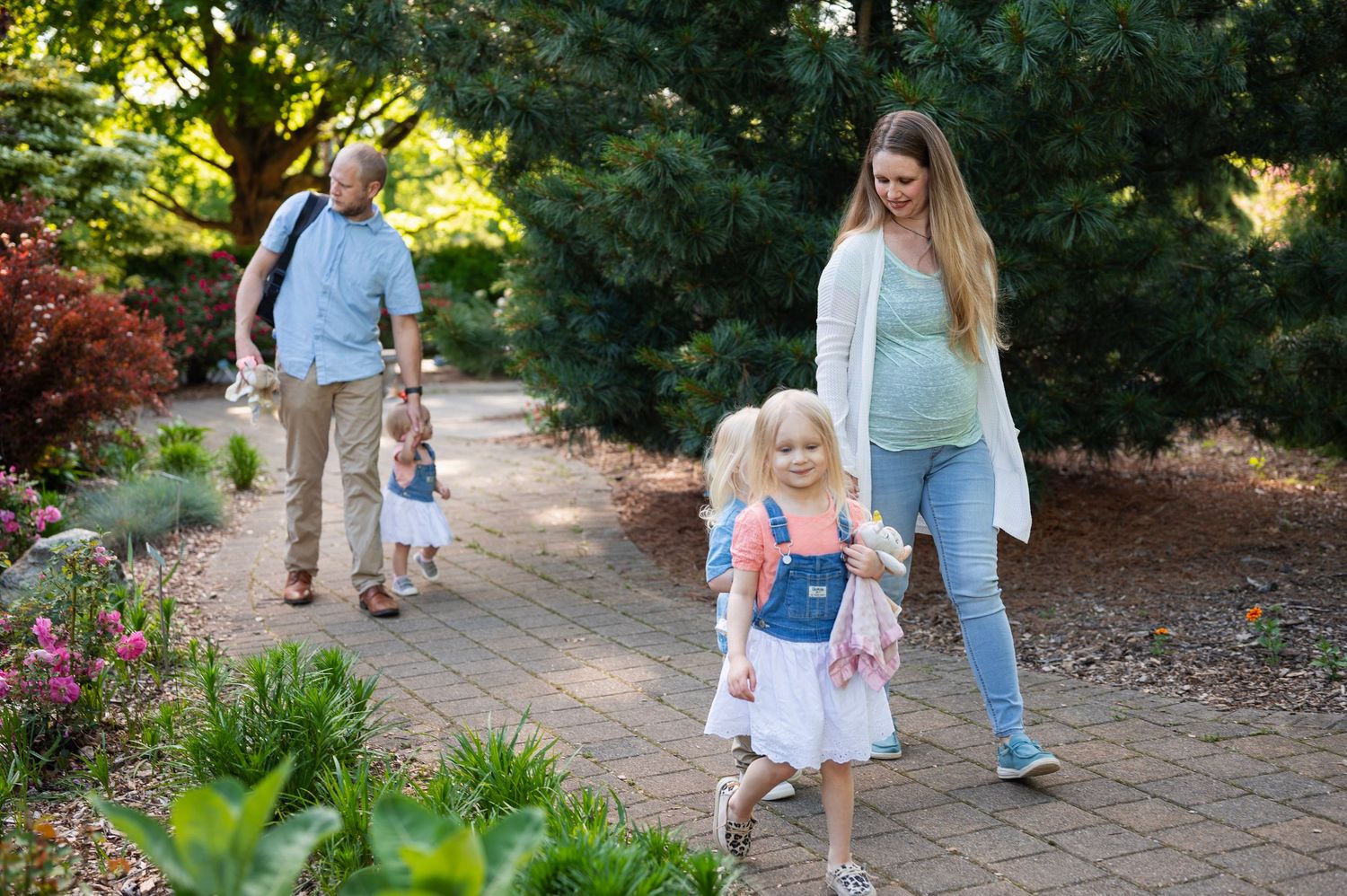Columbus family photographer captures family with young children walking together on a garden path.