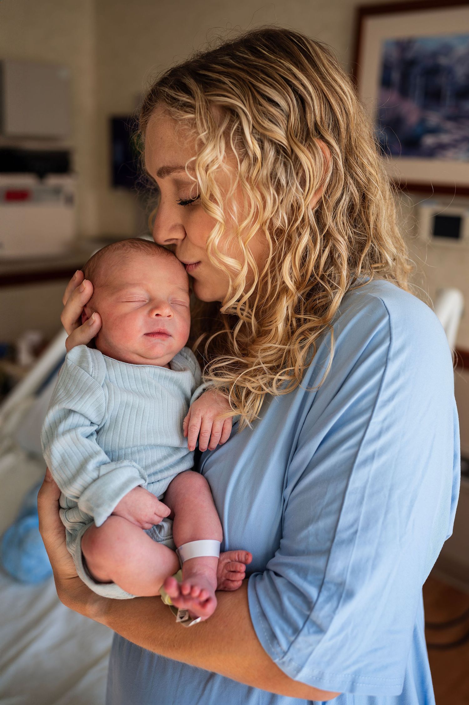 Fresh 48 session with mom kissing her newborn’s head, captured in-hospital with natural light and storytelling intimacy.