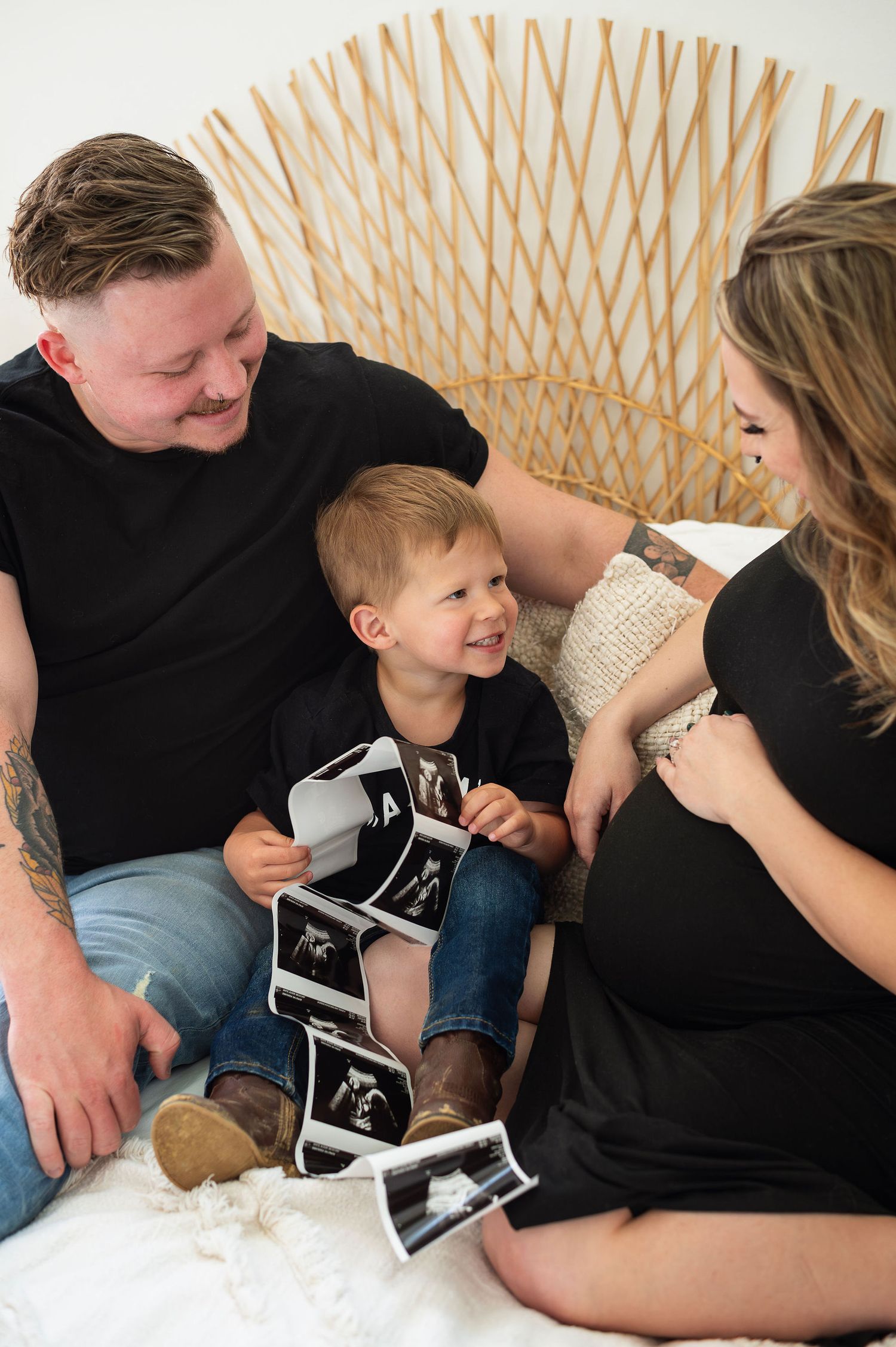 Big brother holding ultrasound prints while mom cradles her bump during a Columbus maternity milestone session full of joy.