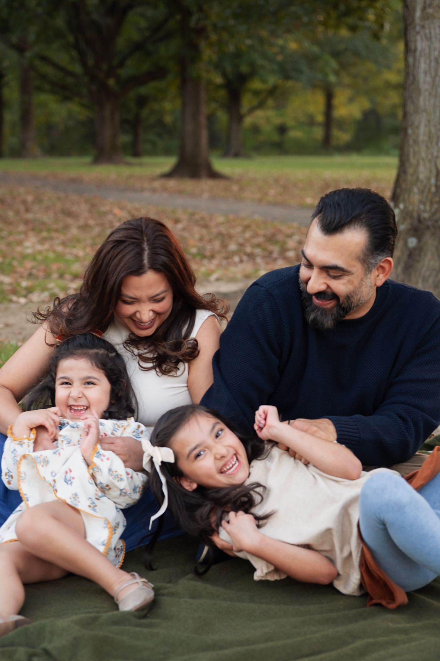 Mom and dad tickling their two laughing daughters on a blanket during a playful fall family session in central Ohio.